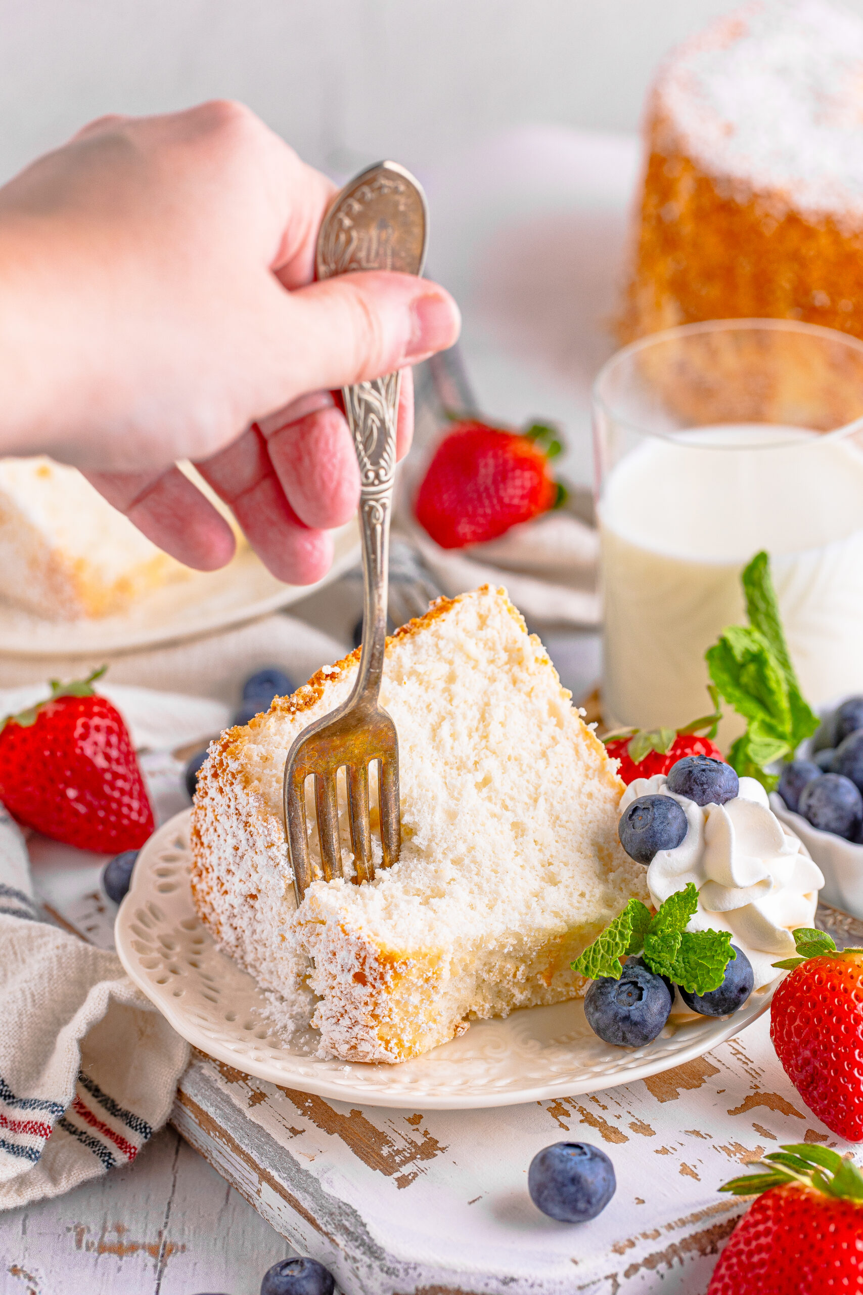 A fork removing a bite of cake from a white plate. 