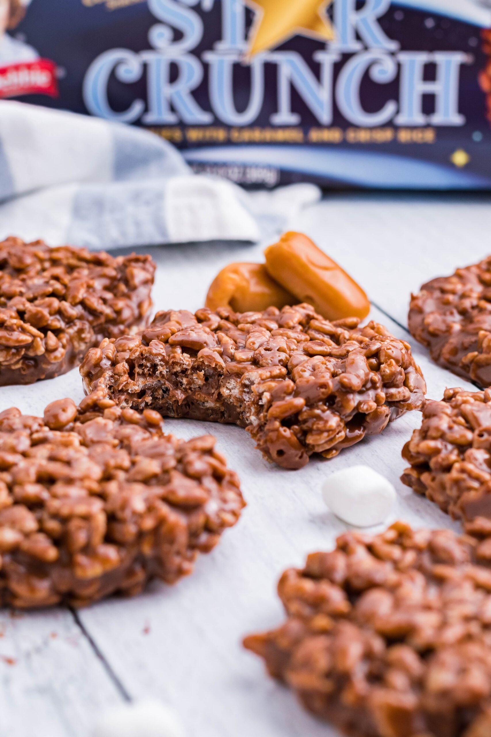 Star Crunch cookies on a white wooden surface with a bite removed showing the inside of the cookie.