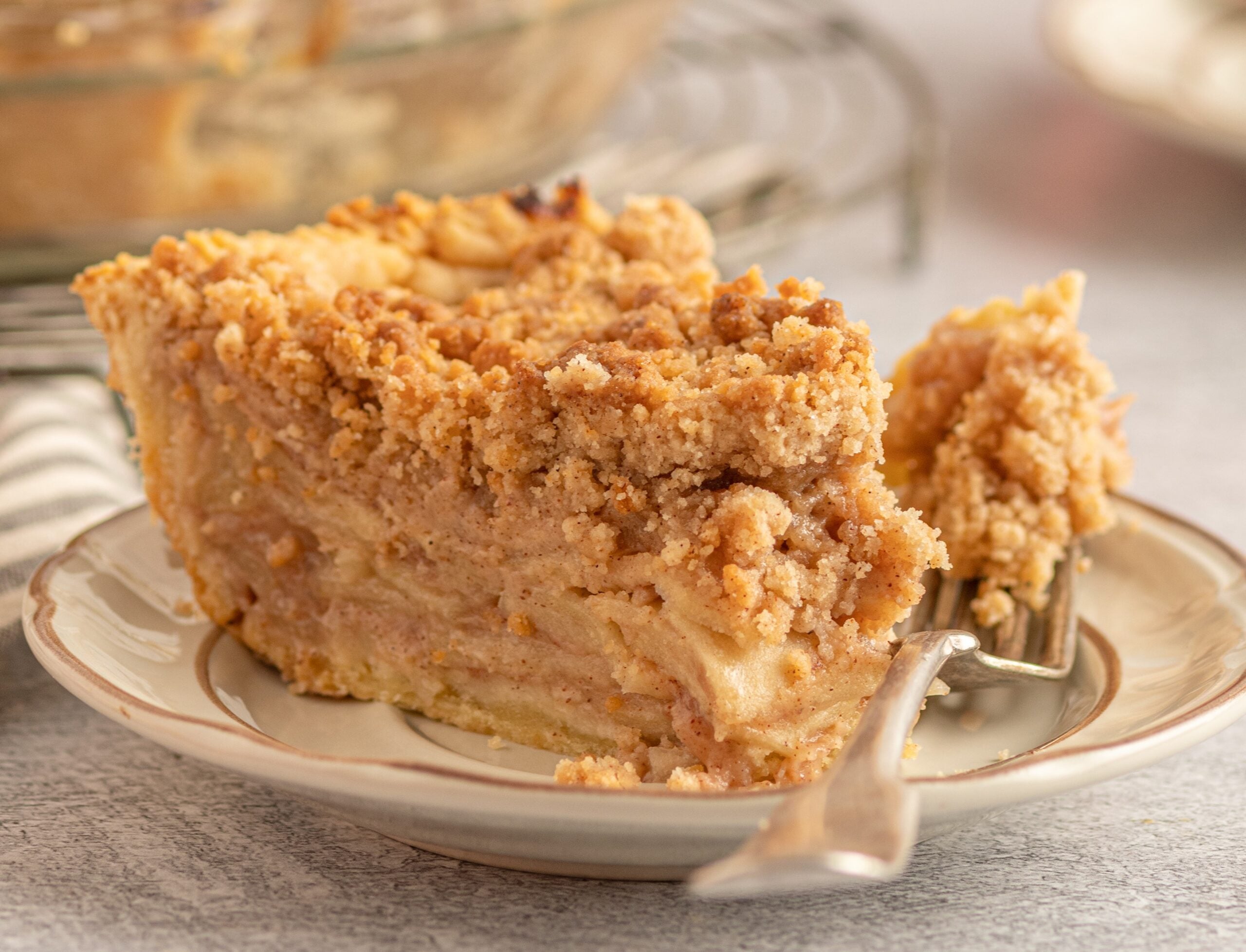 Dutch apple pie slice o a play with a fork bite laying next to it.