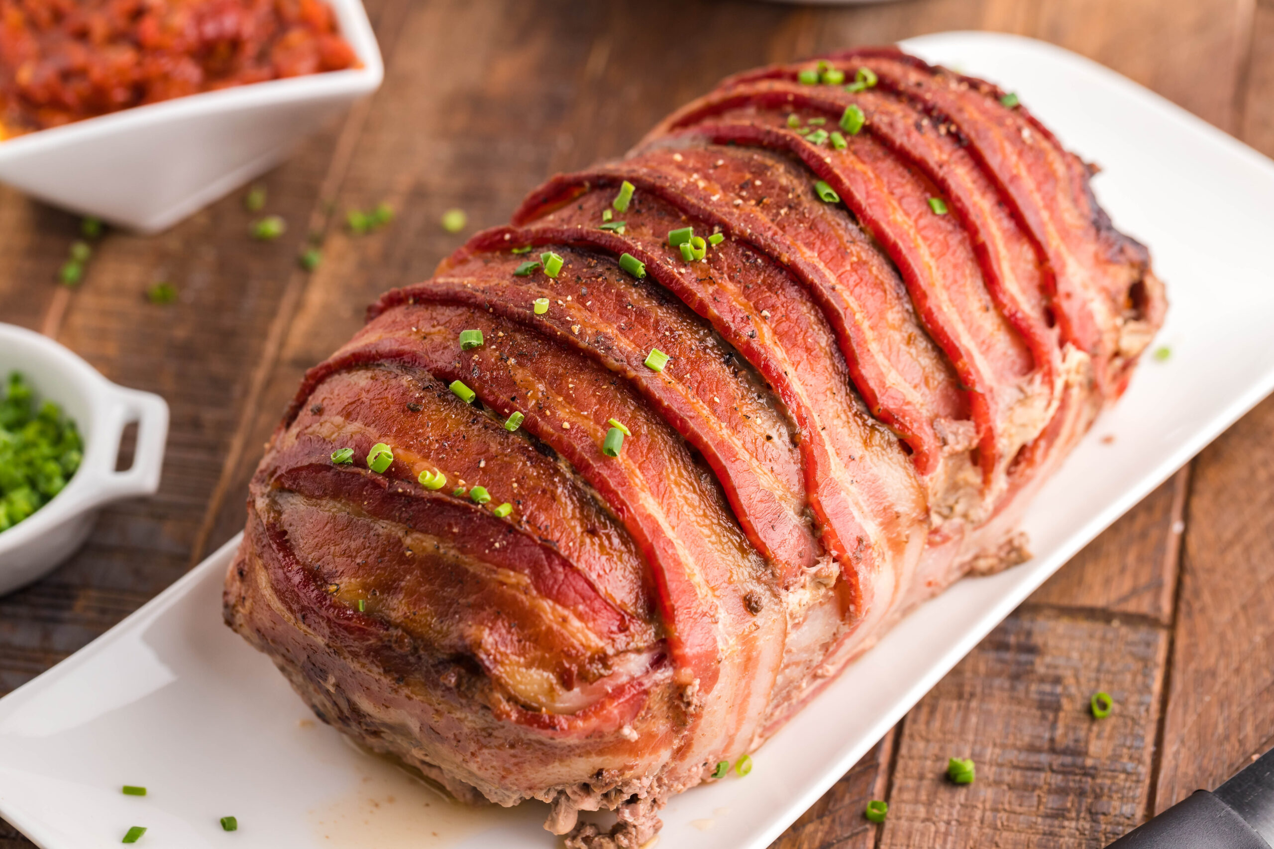 Bacon Wrapped Meatloaf on a white serving plate uncut