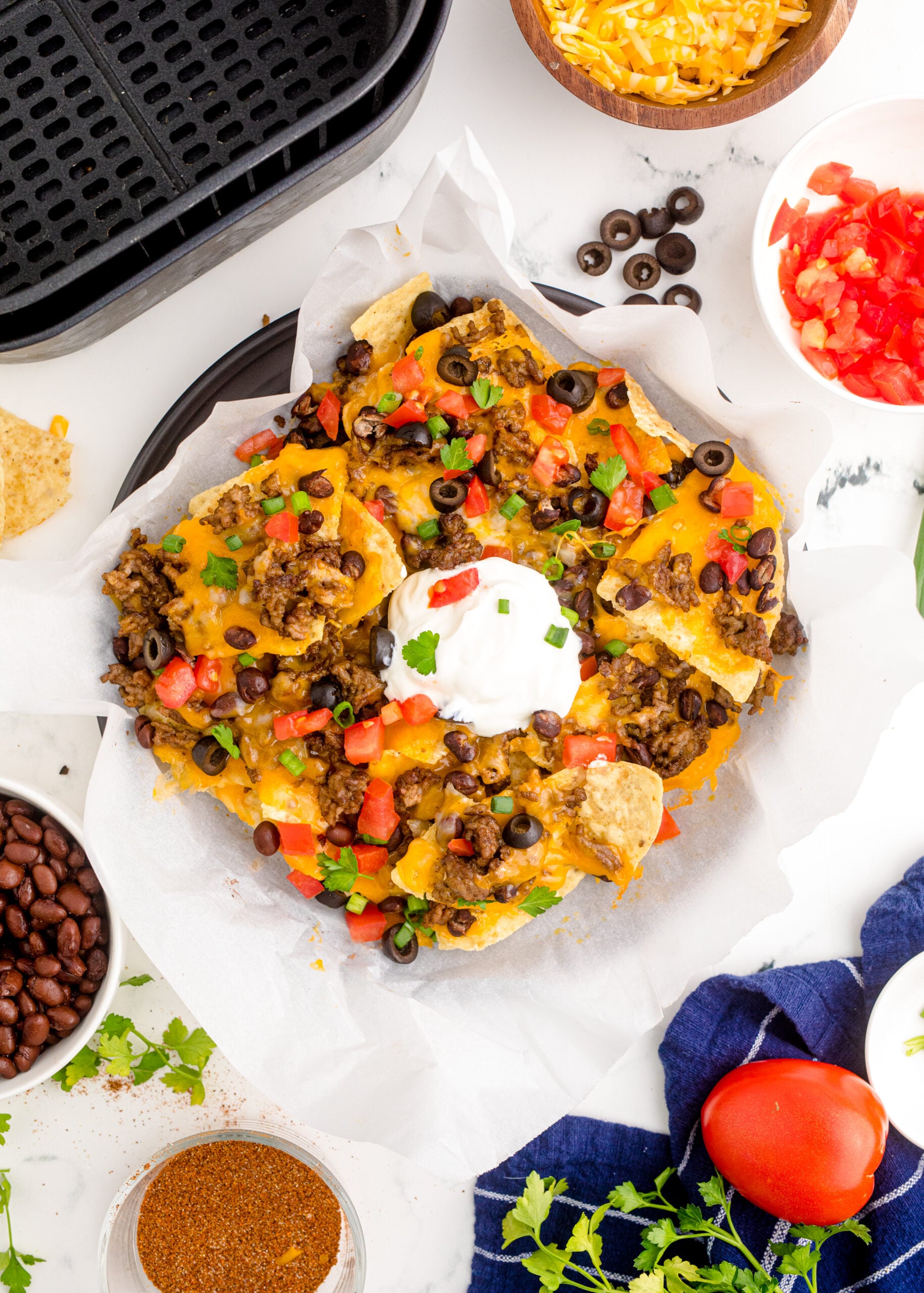 Overhead view of Air Fryer Nachos in an black dish with parchment paper.