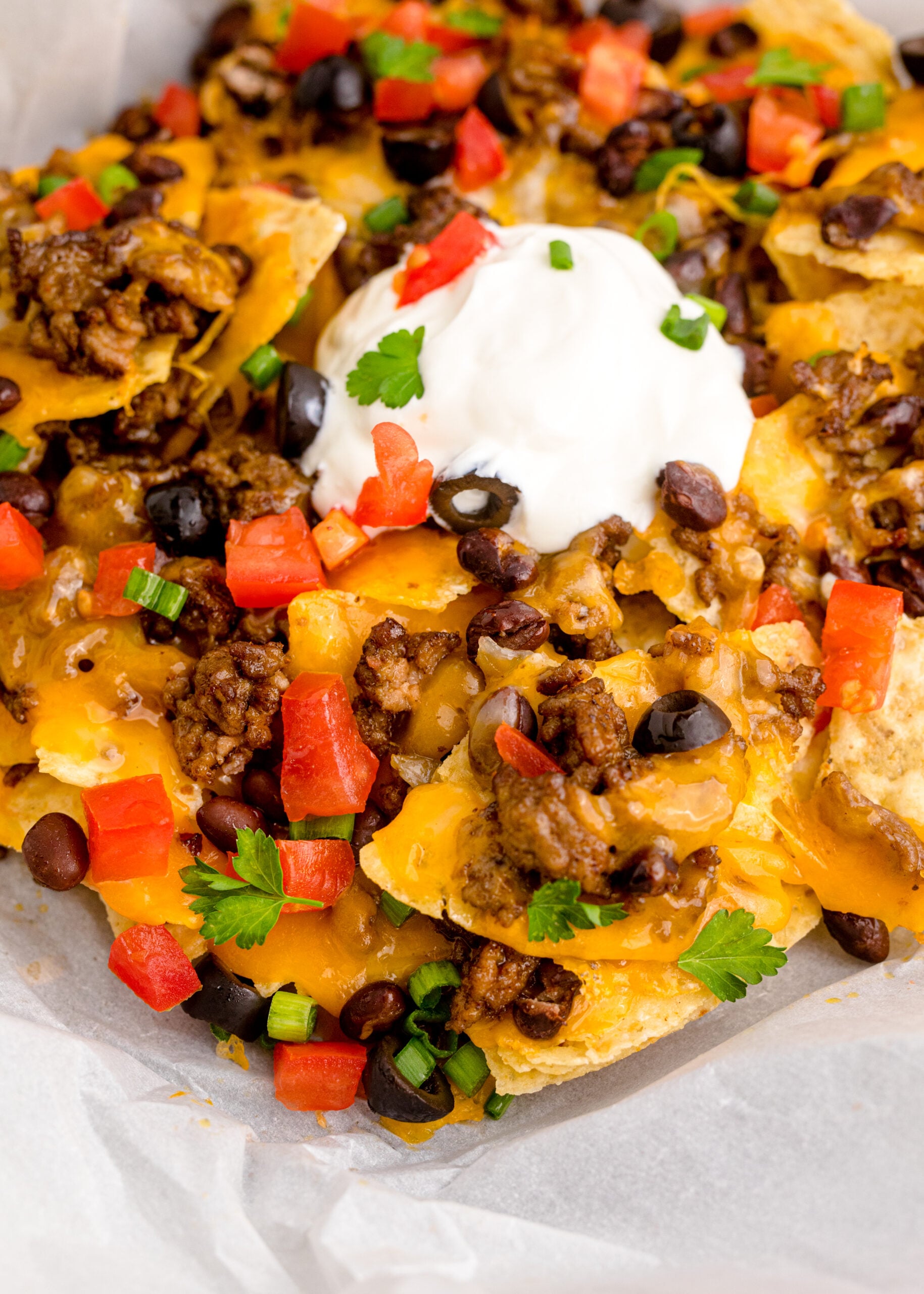 Close up view of Air Fryer Nachos in an black dish with parchment paper.