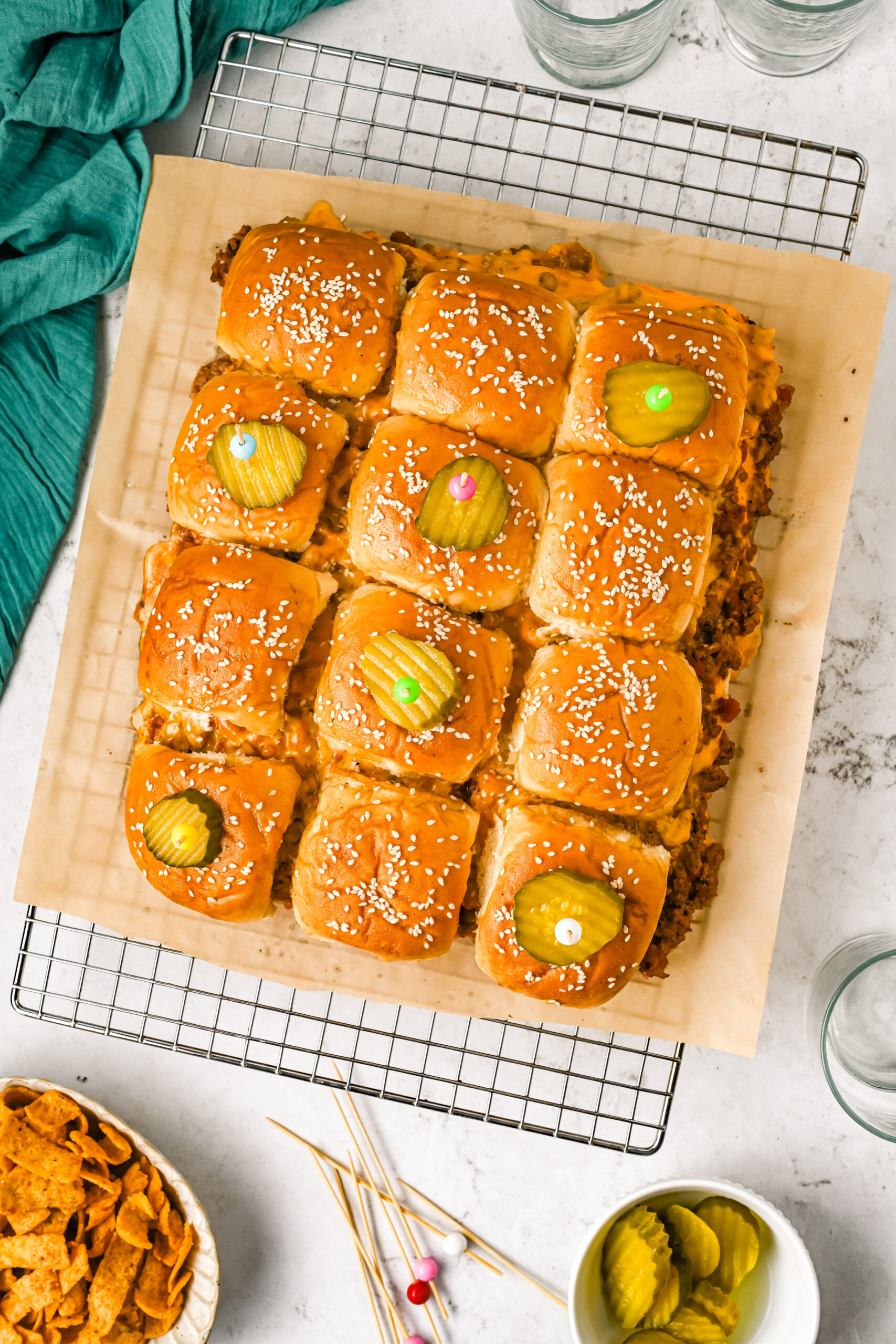 Overhead view of Cheeseburger Sliders on a wire rack garnished with pickle slices.