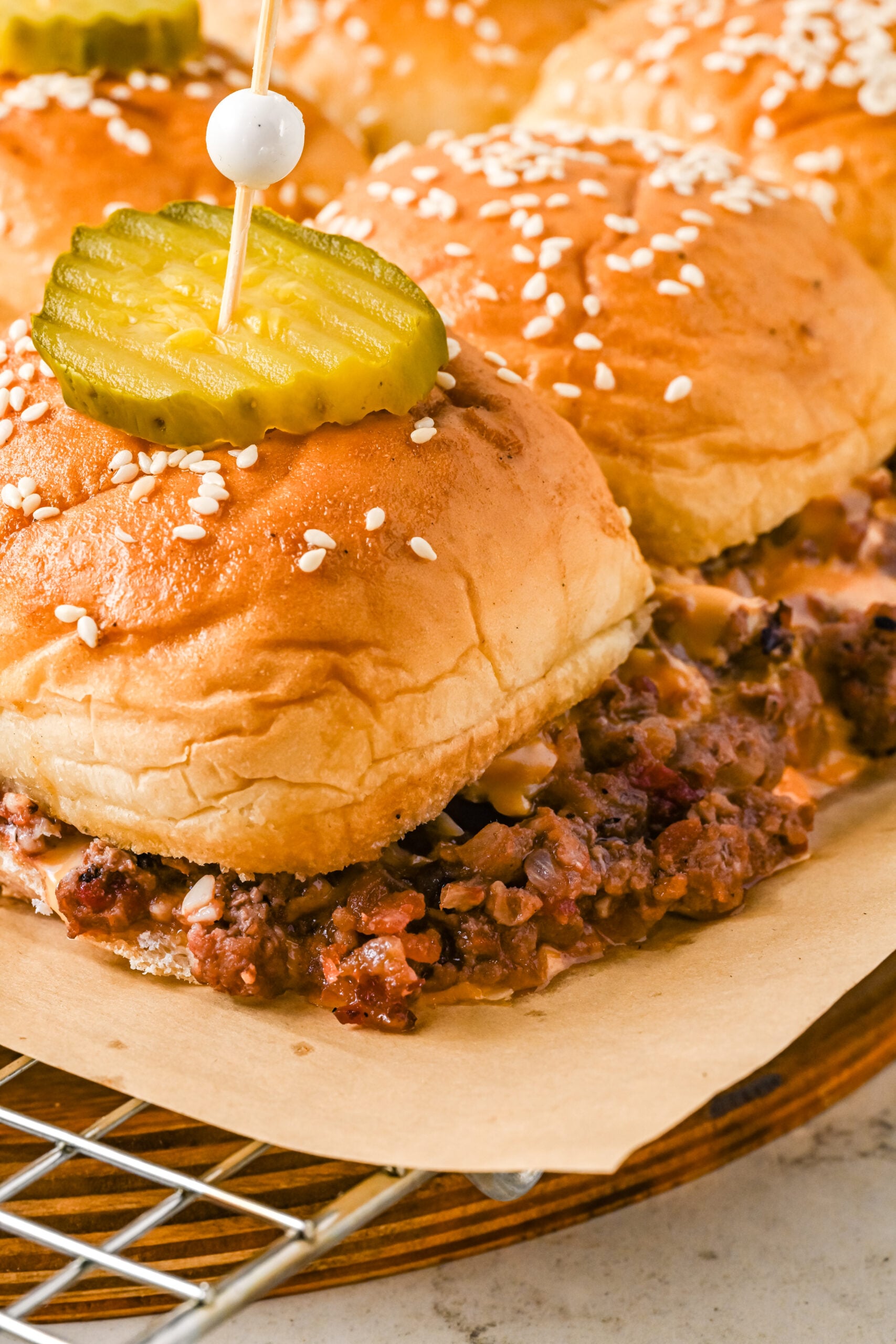 Up close view of Cheeseburger Sliders on a wire rack garnished with pickle slices.