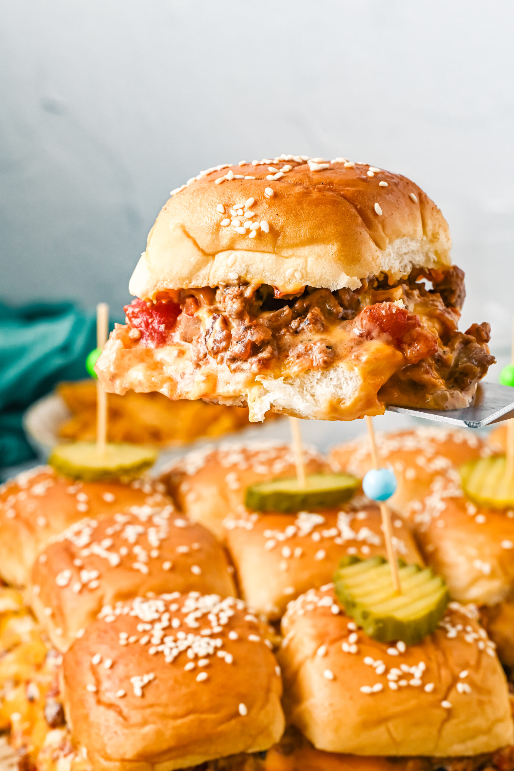 Front view of a Cheeseburger Slider on a silver spatula.