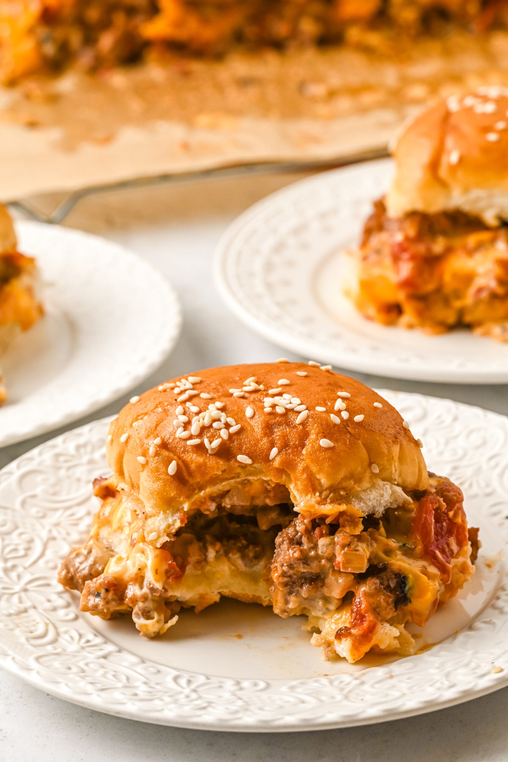 Front view of a Cheeseburger Slider on a white dish with a bite removed.