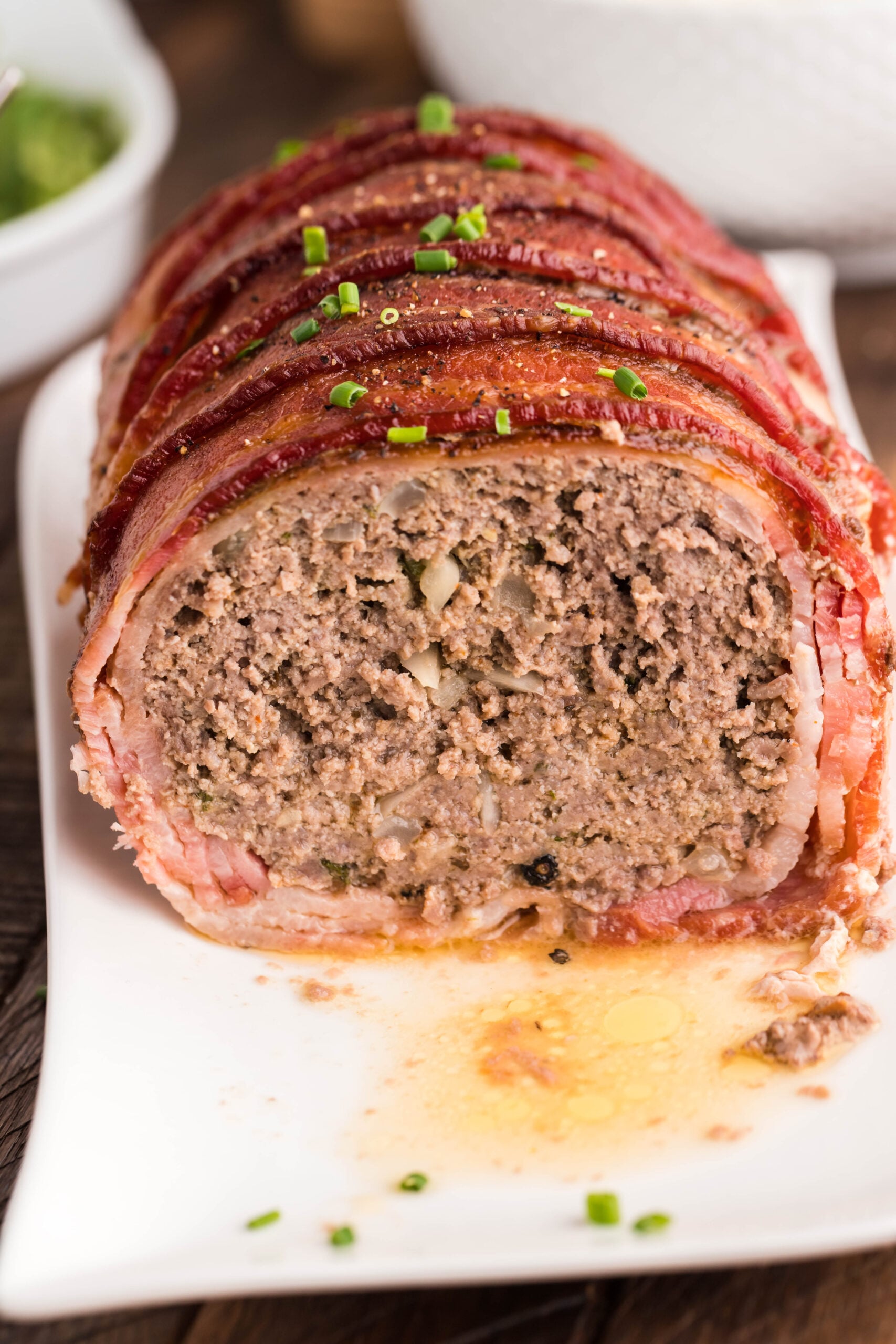 Front view of Bacon Wrapped Meatloaf on a white serving dish.