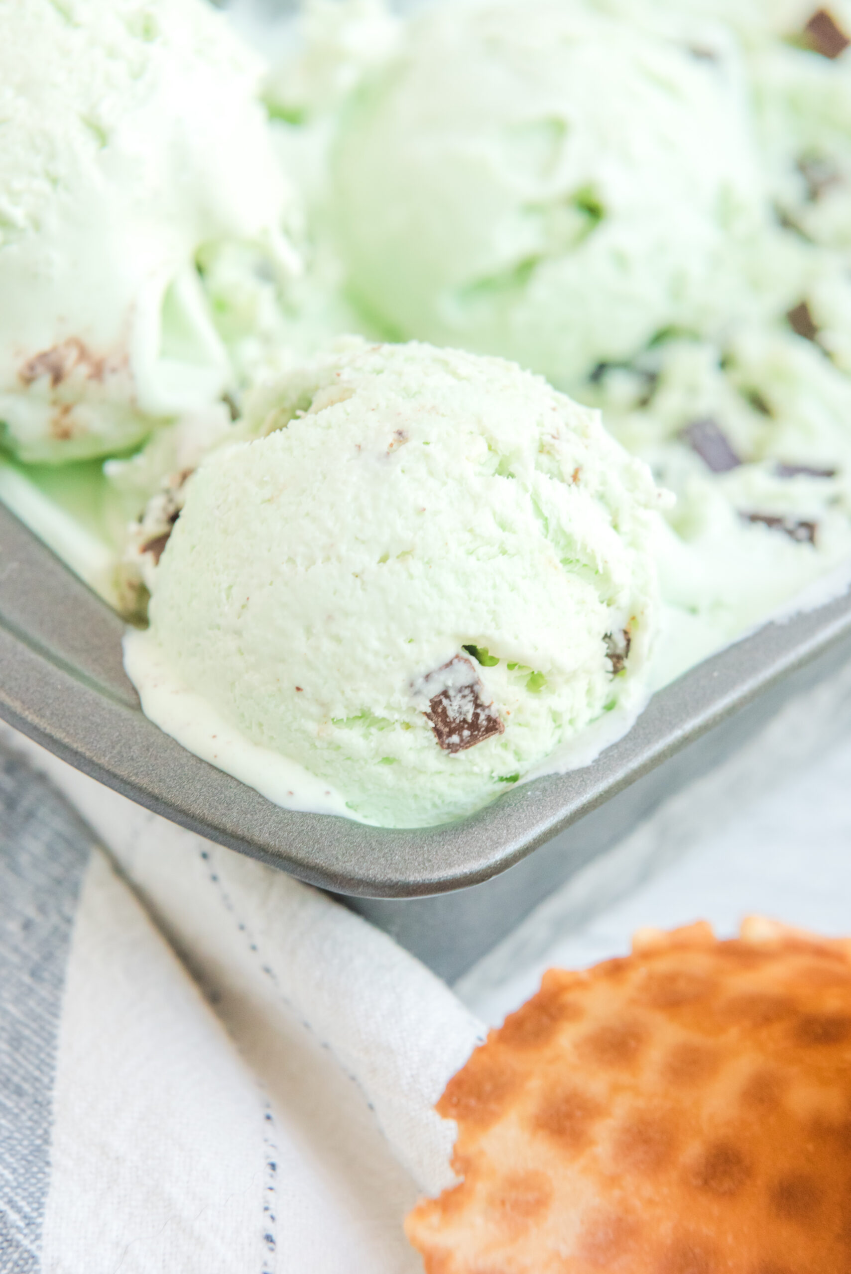 Close up view of a scoop of Mint Chocolate Chip Ice Cream in a silver baking dish.