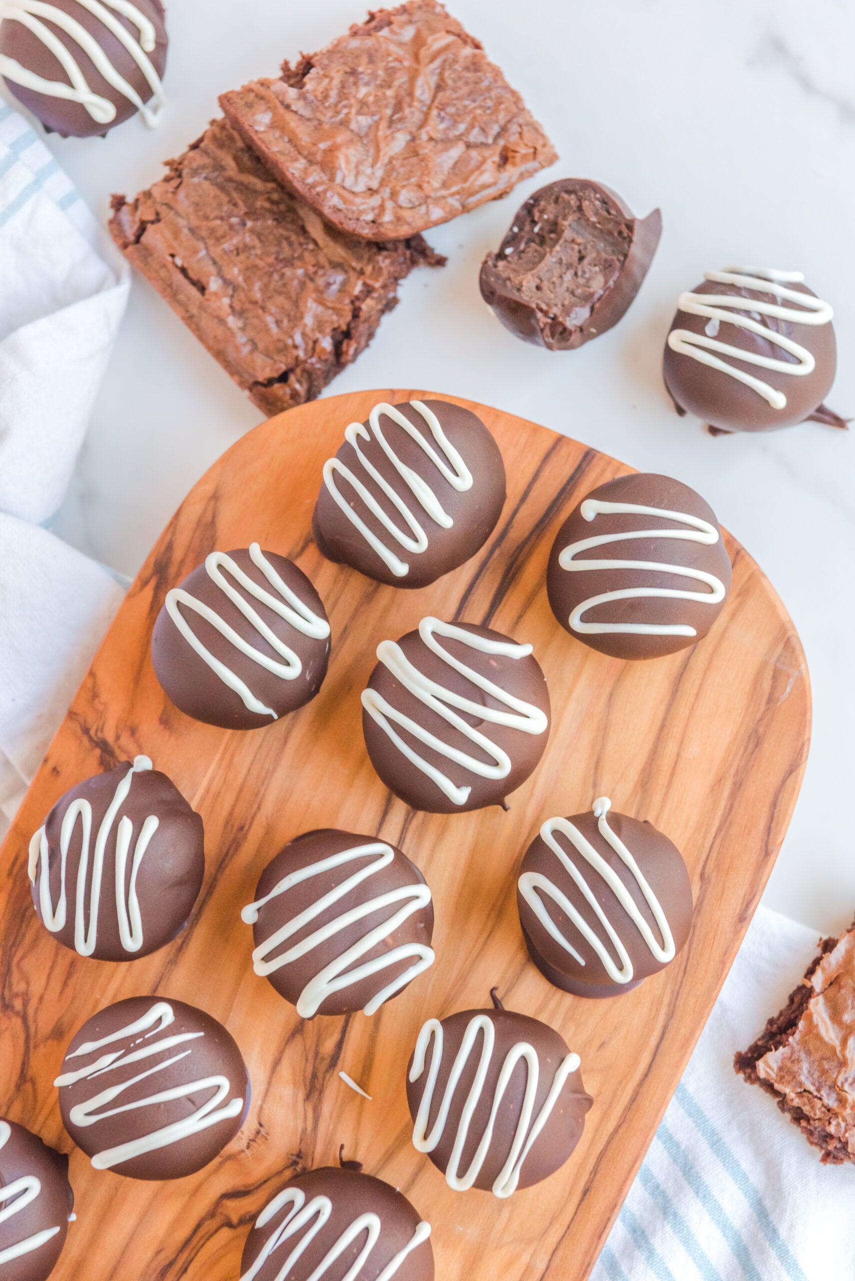 Overhead view of brownie truffles on a wooden serving board with brownies in the background.
