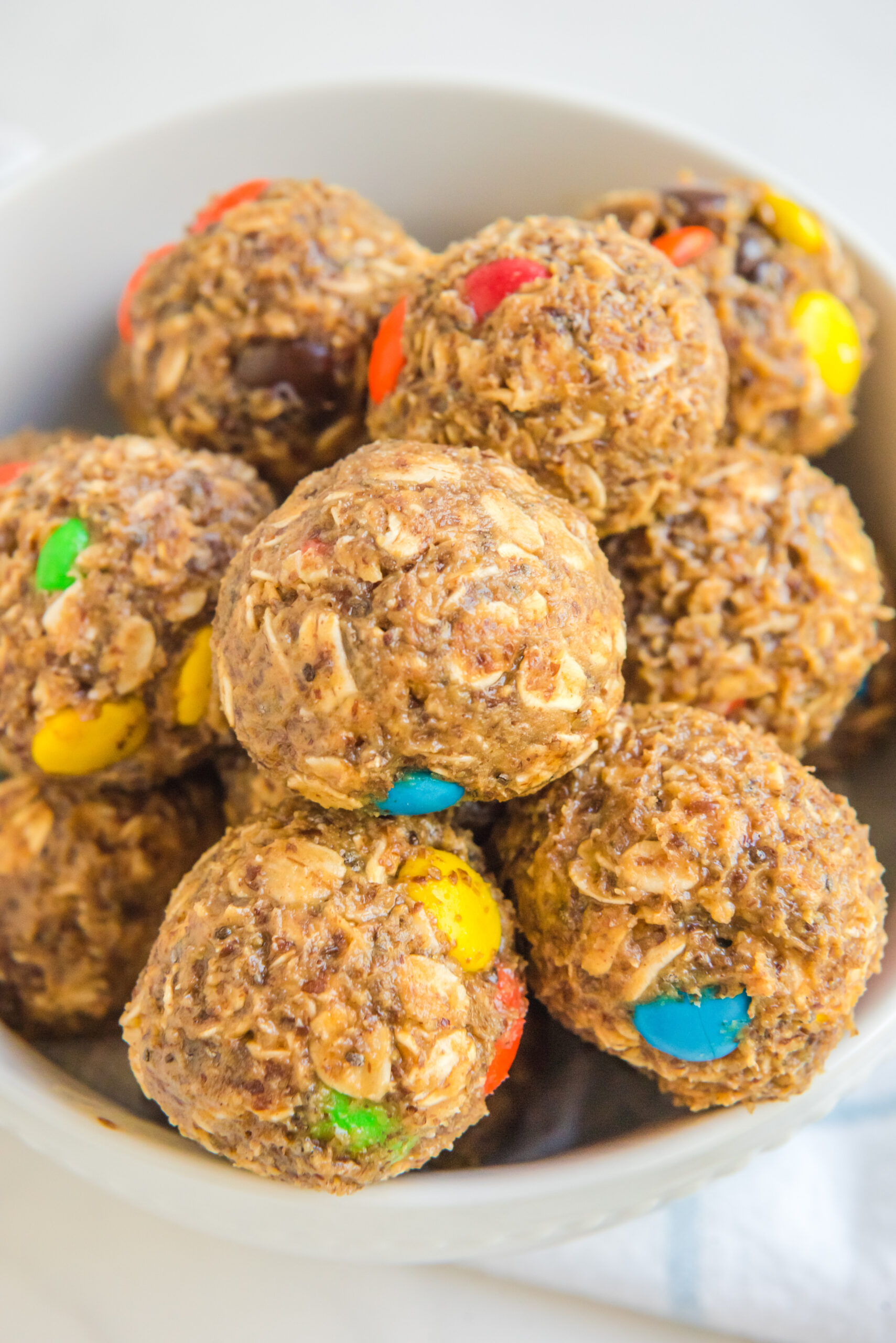Close up view of No Bake M&M Energy balls in a white bowl.