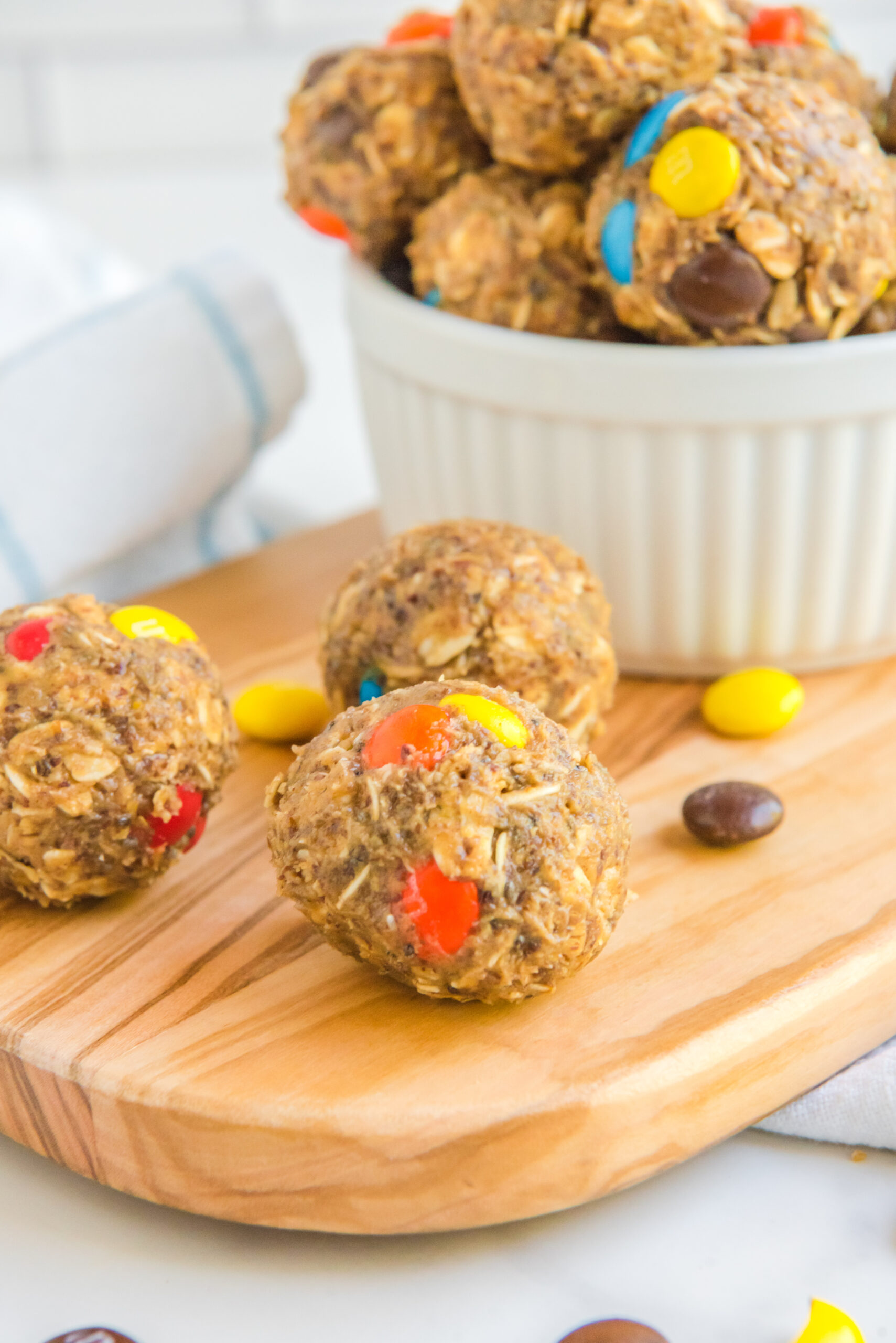 Side view of No Bake M&M Energy Balls on a wooden cutting board.
