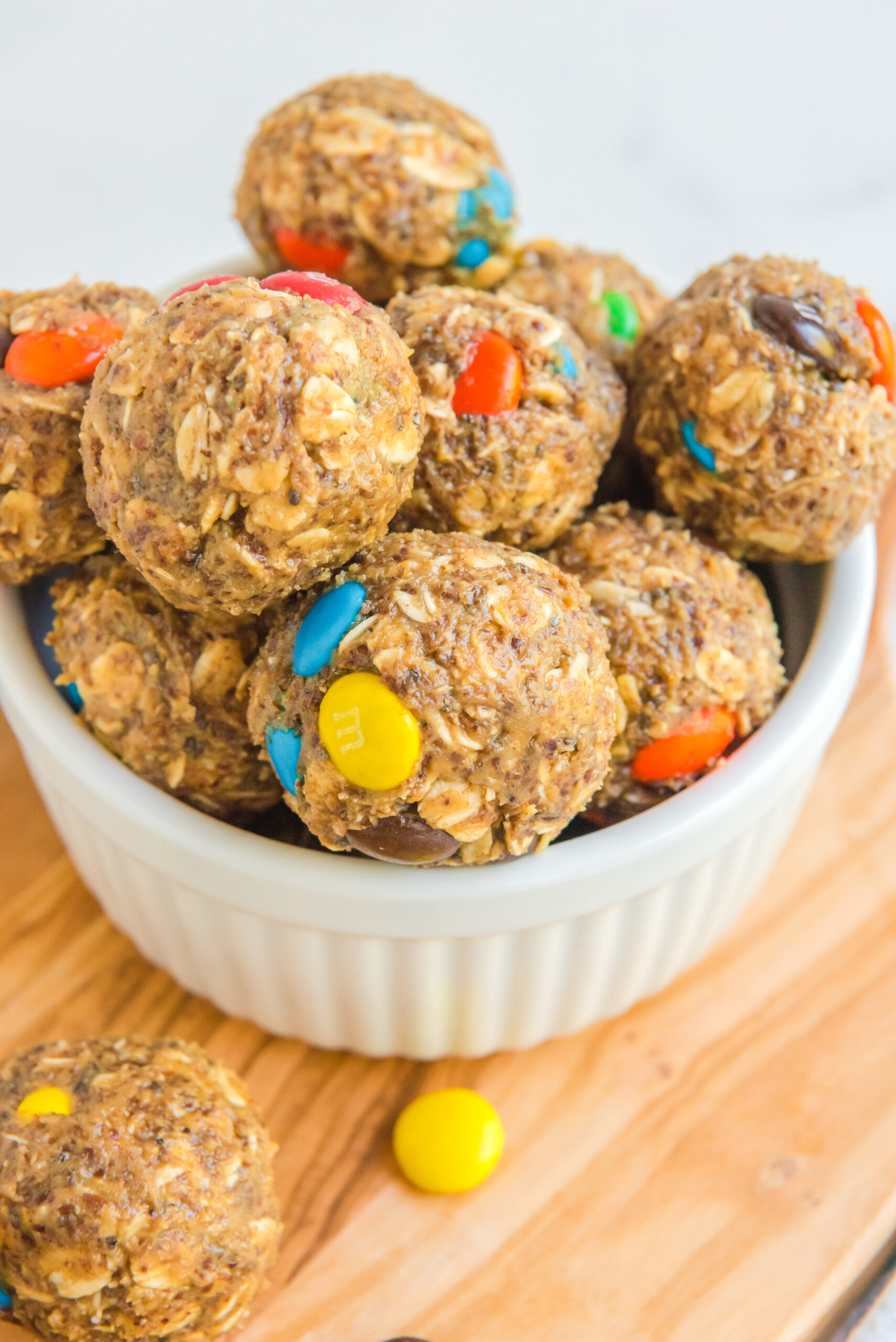 Close up view of No Bake M&M Energy balls in a white bowl.