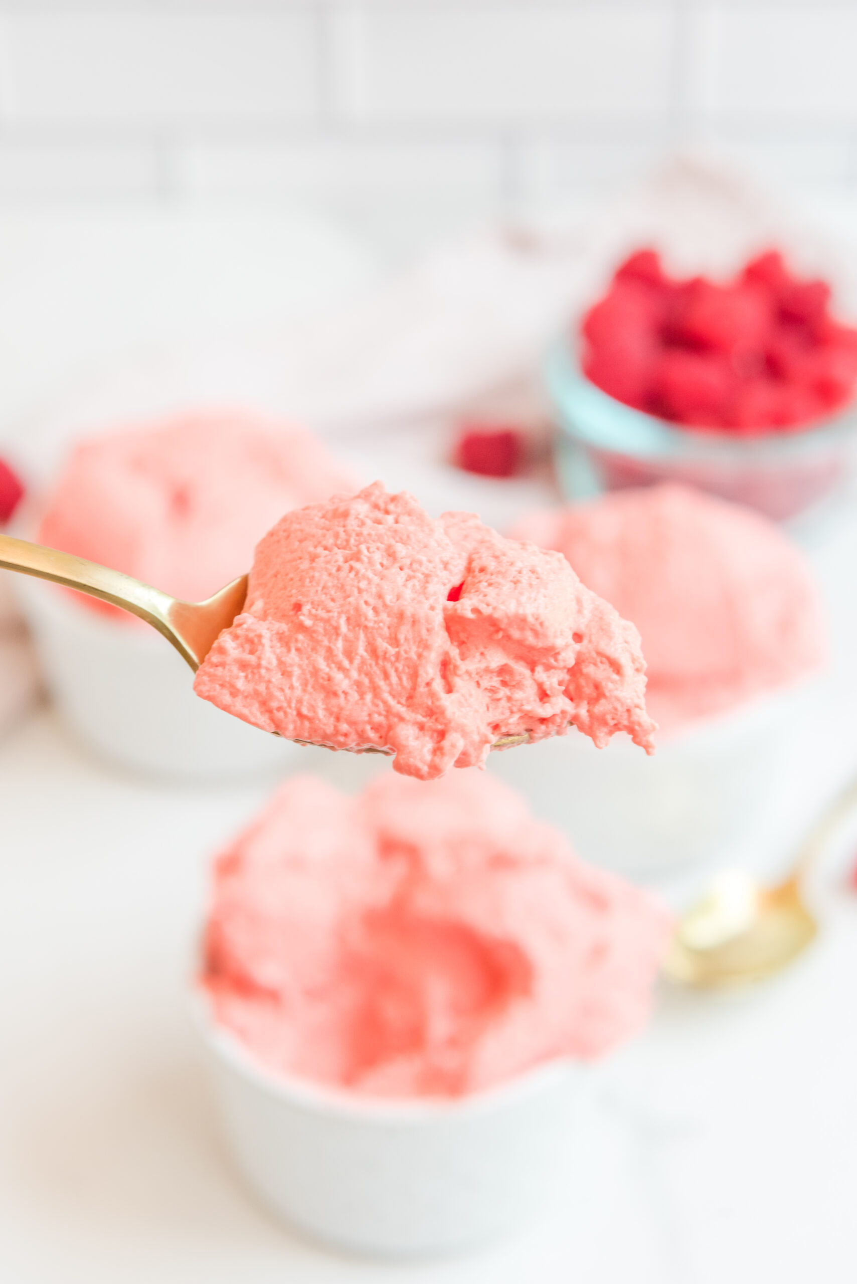 Front view of a gold spoon with a spoon full of Raspberry Jello Fluff.