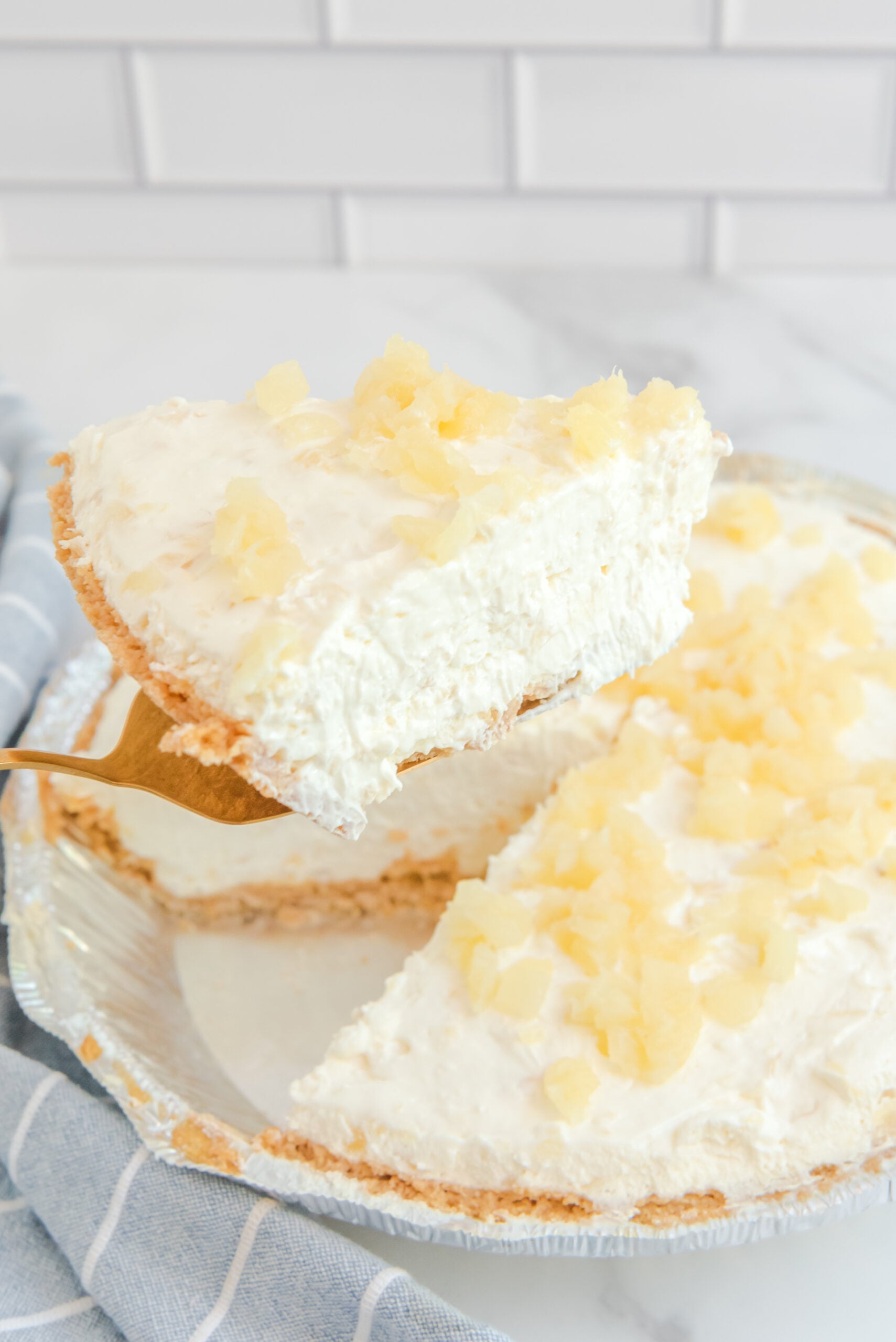Side view of a slice of No Bake Pineapple Cheesecake on a gold cake server.