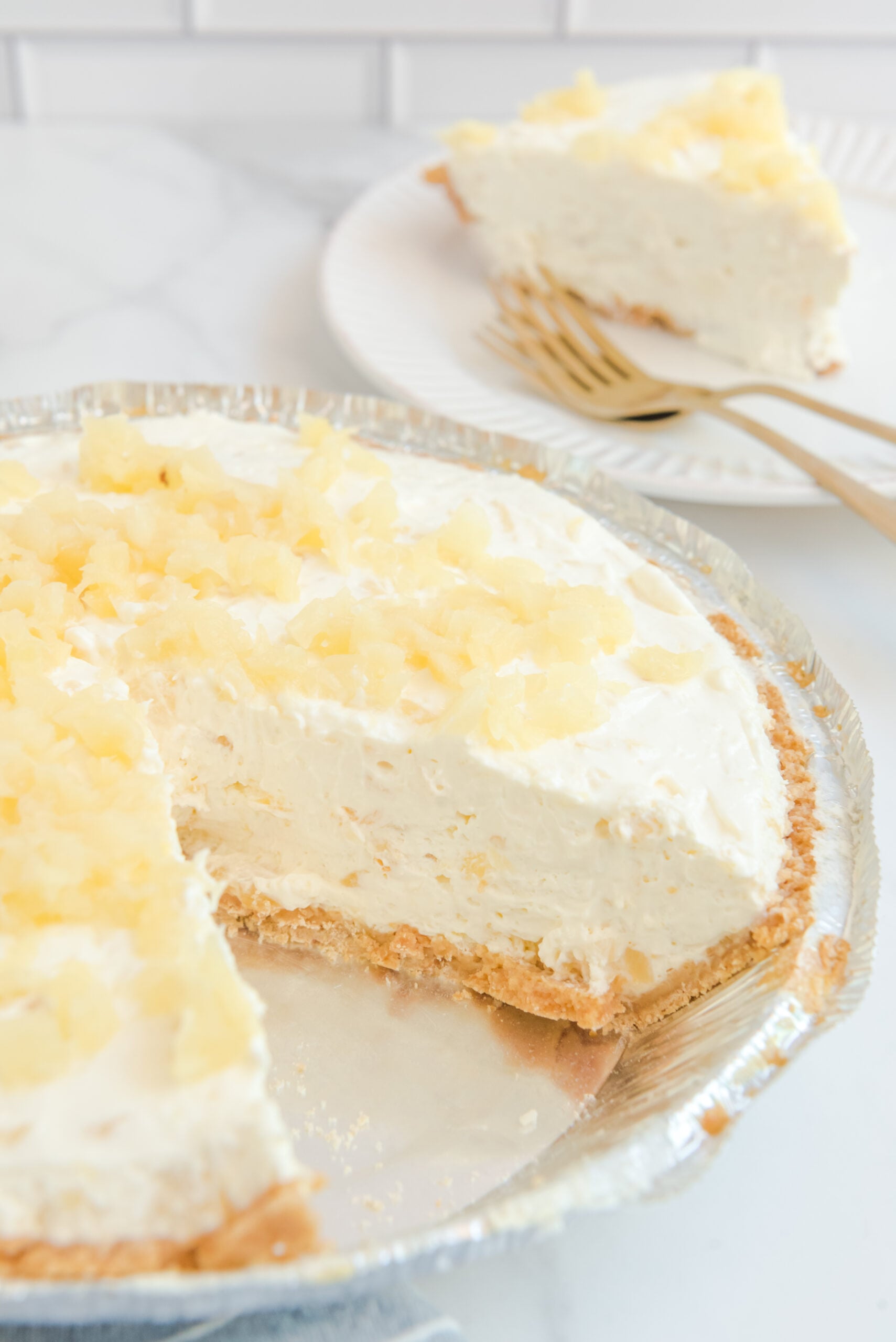 No Bake Pineapple Cheesecake Pie in a pie plate with a slice removed