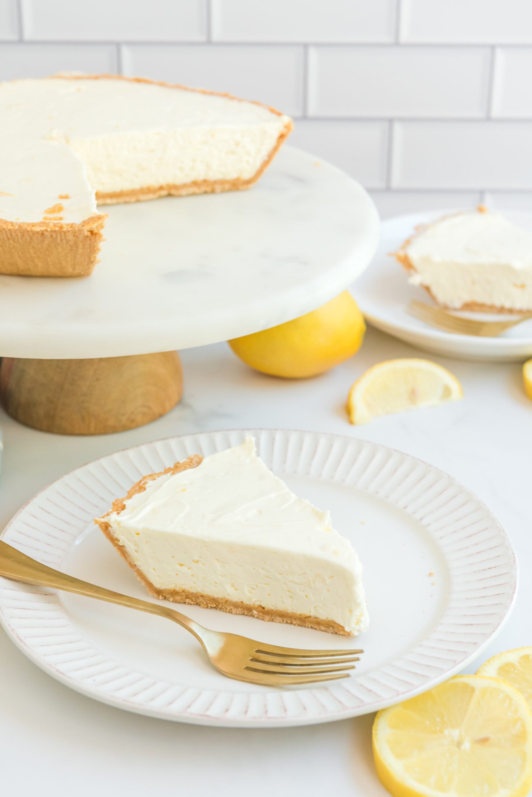 Front view of No Bake Lemon Cheesecake on a white plate with a gold fork.