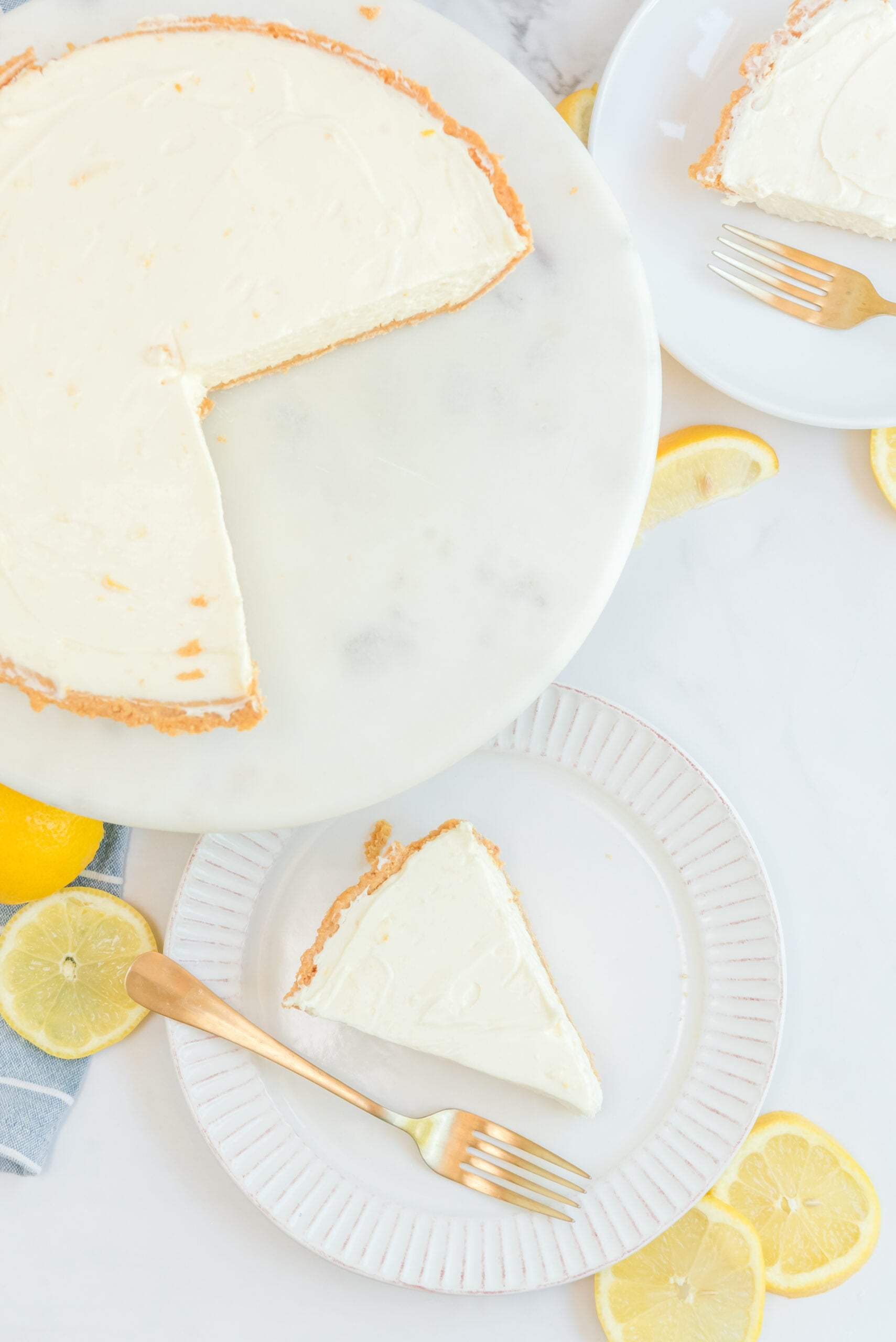Overhead view of No Bake Lemon Cheesecake with two slices removed and on white plates.
