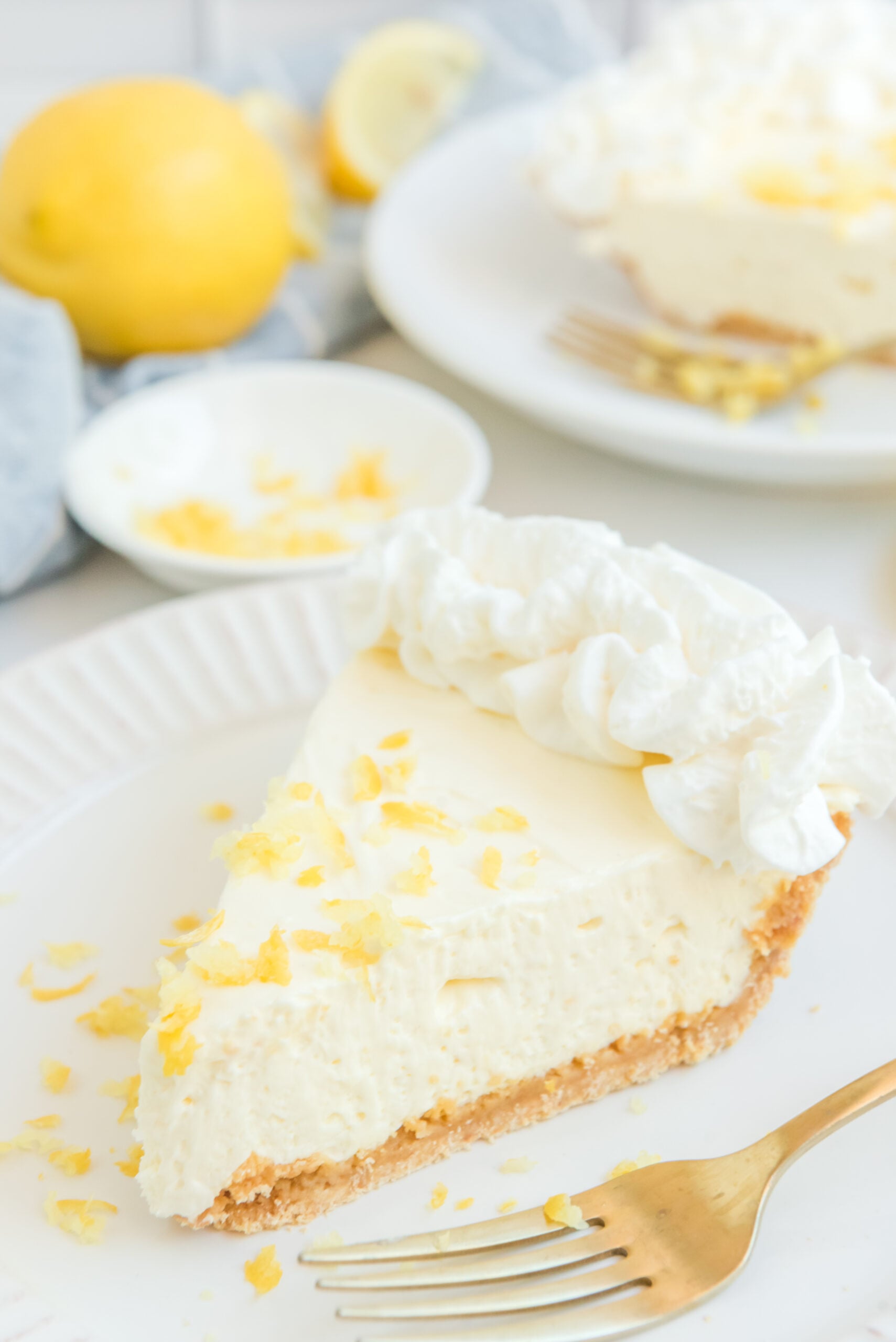 Close up view of a slice of No Bake Lemon Cheesecake garnished with whipped cream and lemon zest.