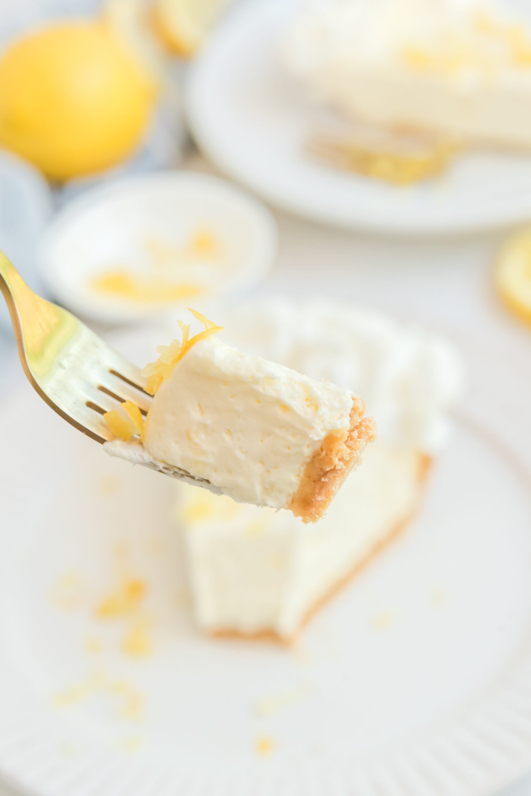 Close up view of a bite of No Bake Lemon Cheesecake on a gold fork.