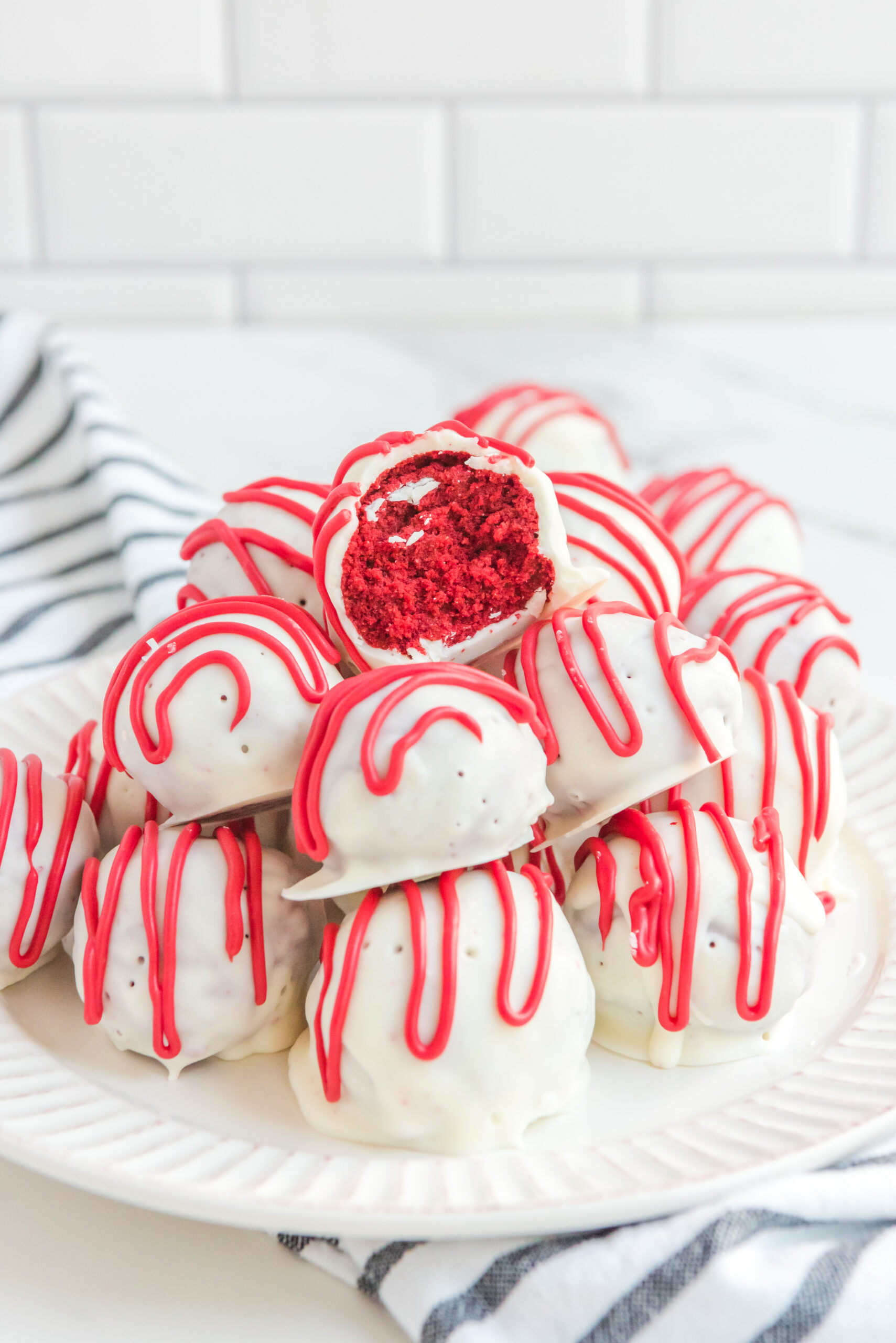 A large bowl filled with red velvet cake balls with the center ball with a bite removed.