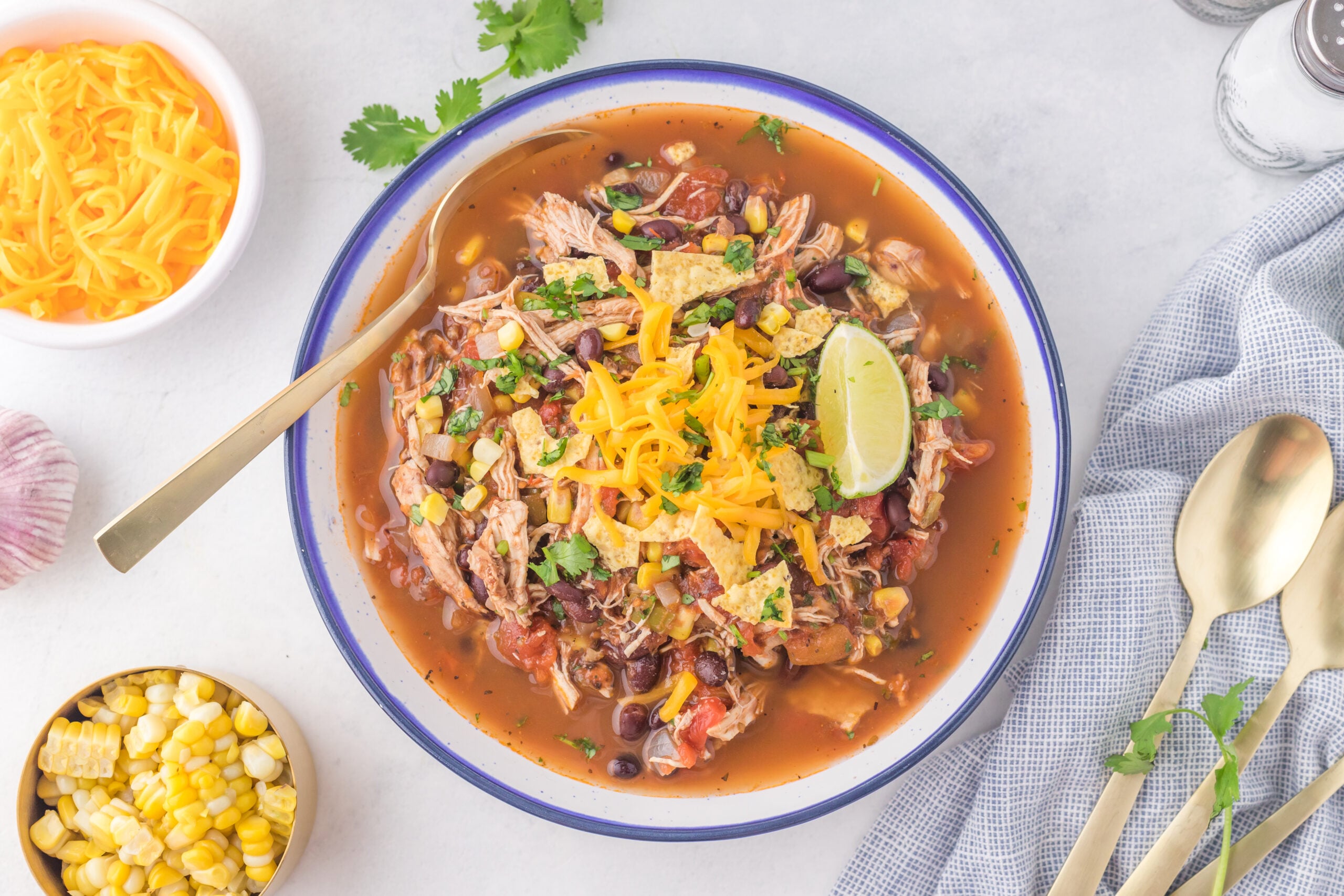 Overhead view of Chicken Taco Soup in a bowl served with a golden spoon.