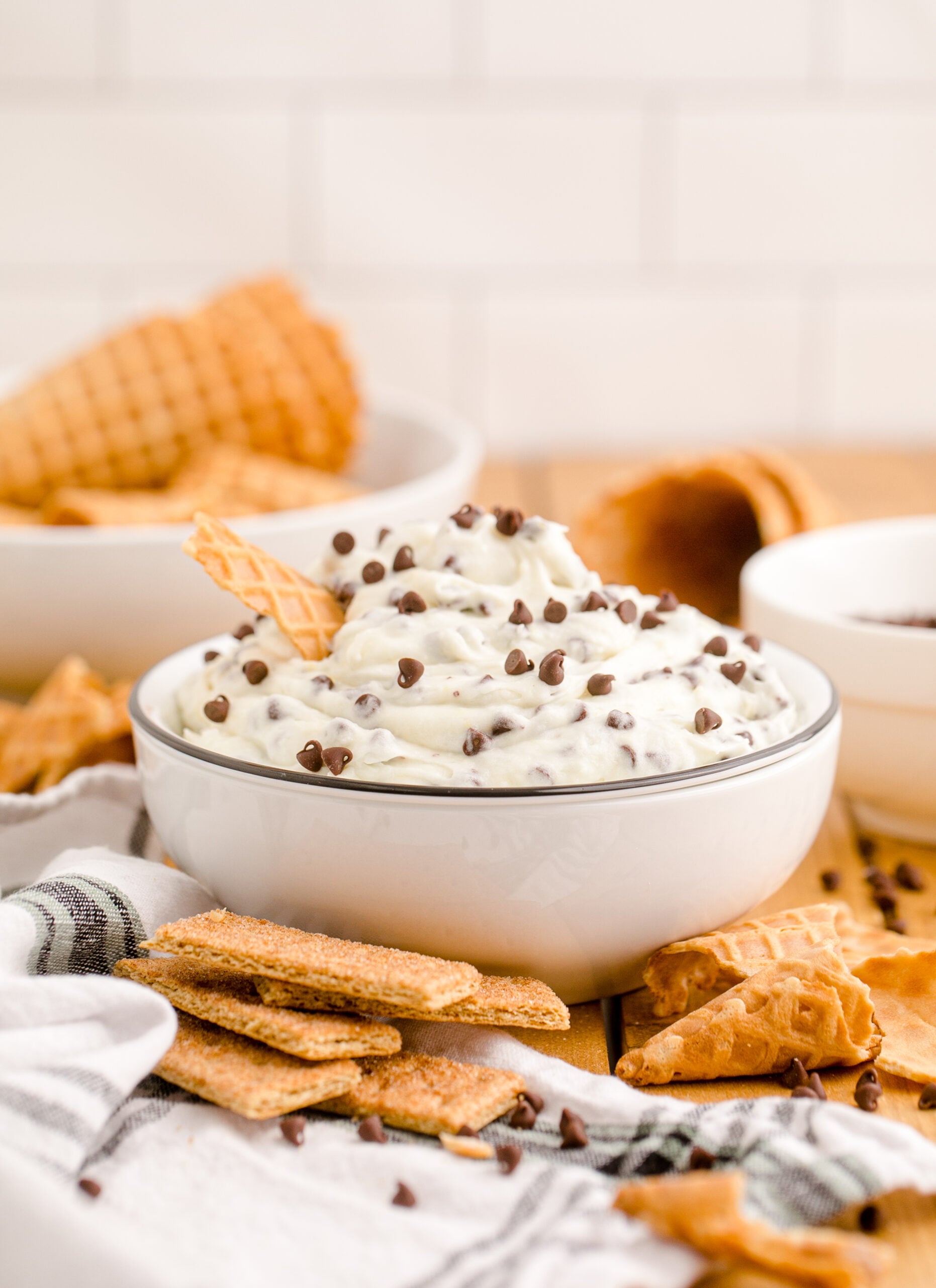 Side view of Cannoli Dip in a black and white dish with a piece of waffle cone.