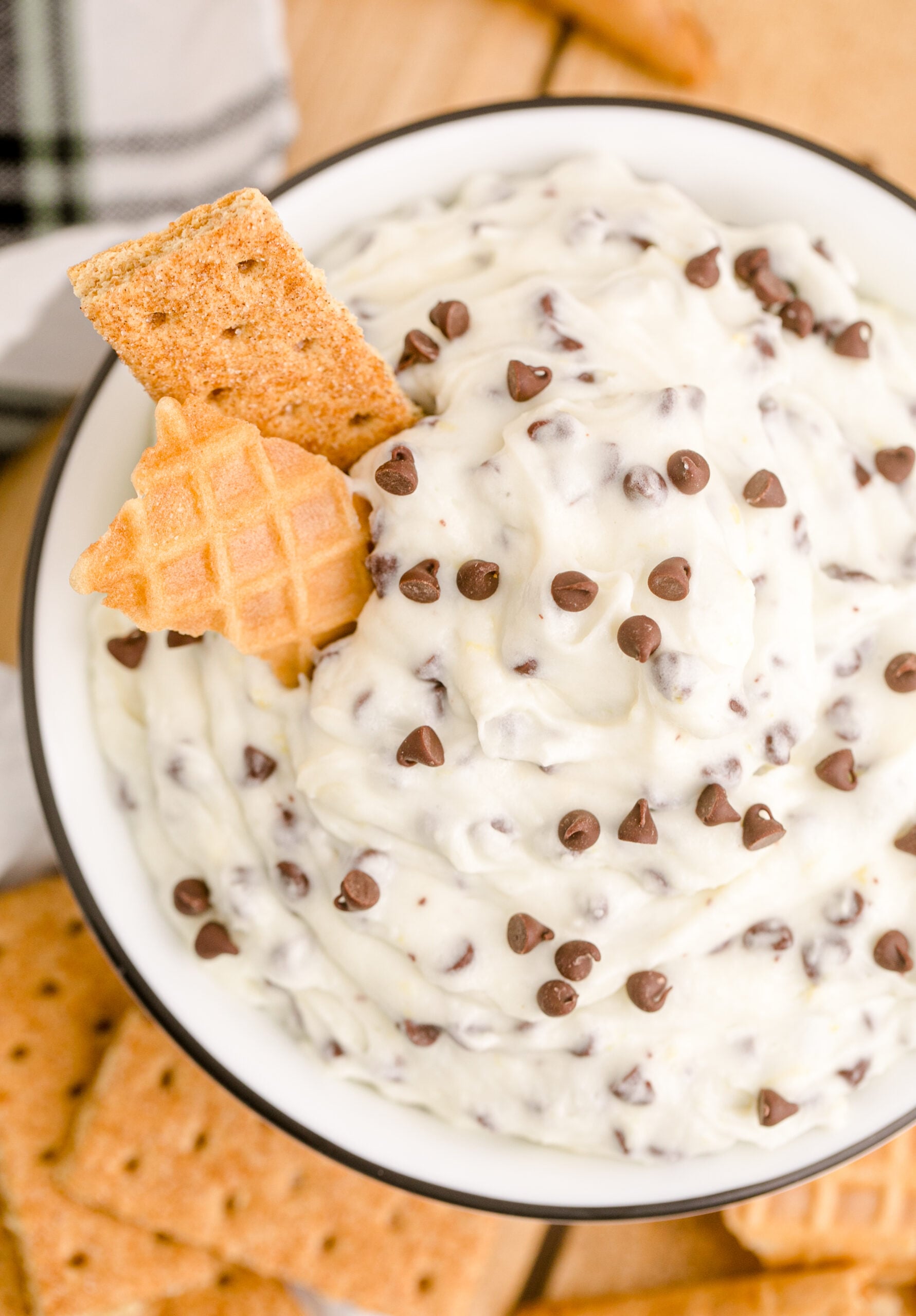 Up close overhead view of Cannoli Dip in a black and white dish with a piece of waffle cone and graham cracker.