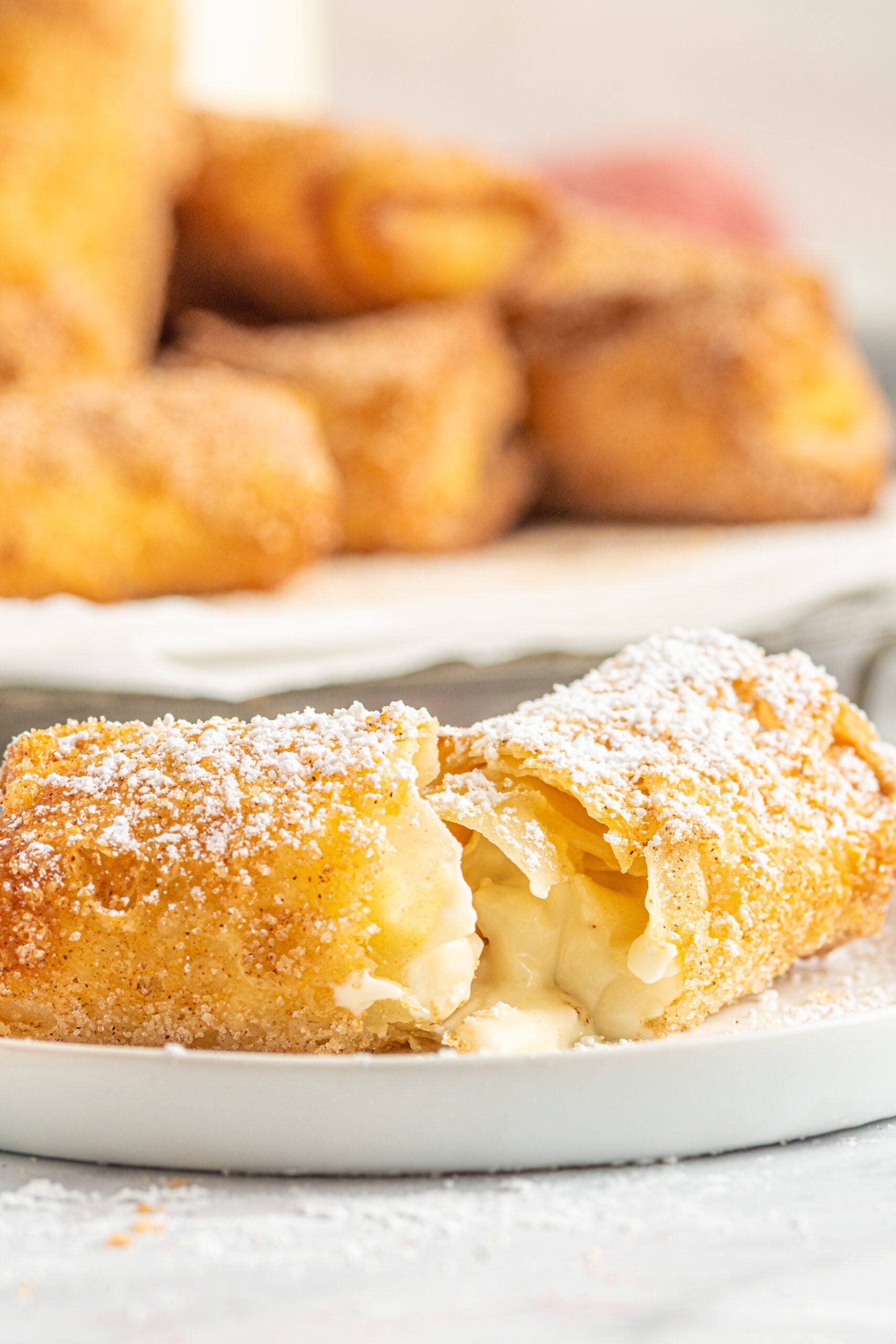 Side view of a Cheesecake Egg Roll split in half on a white plate.