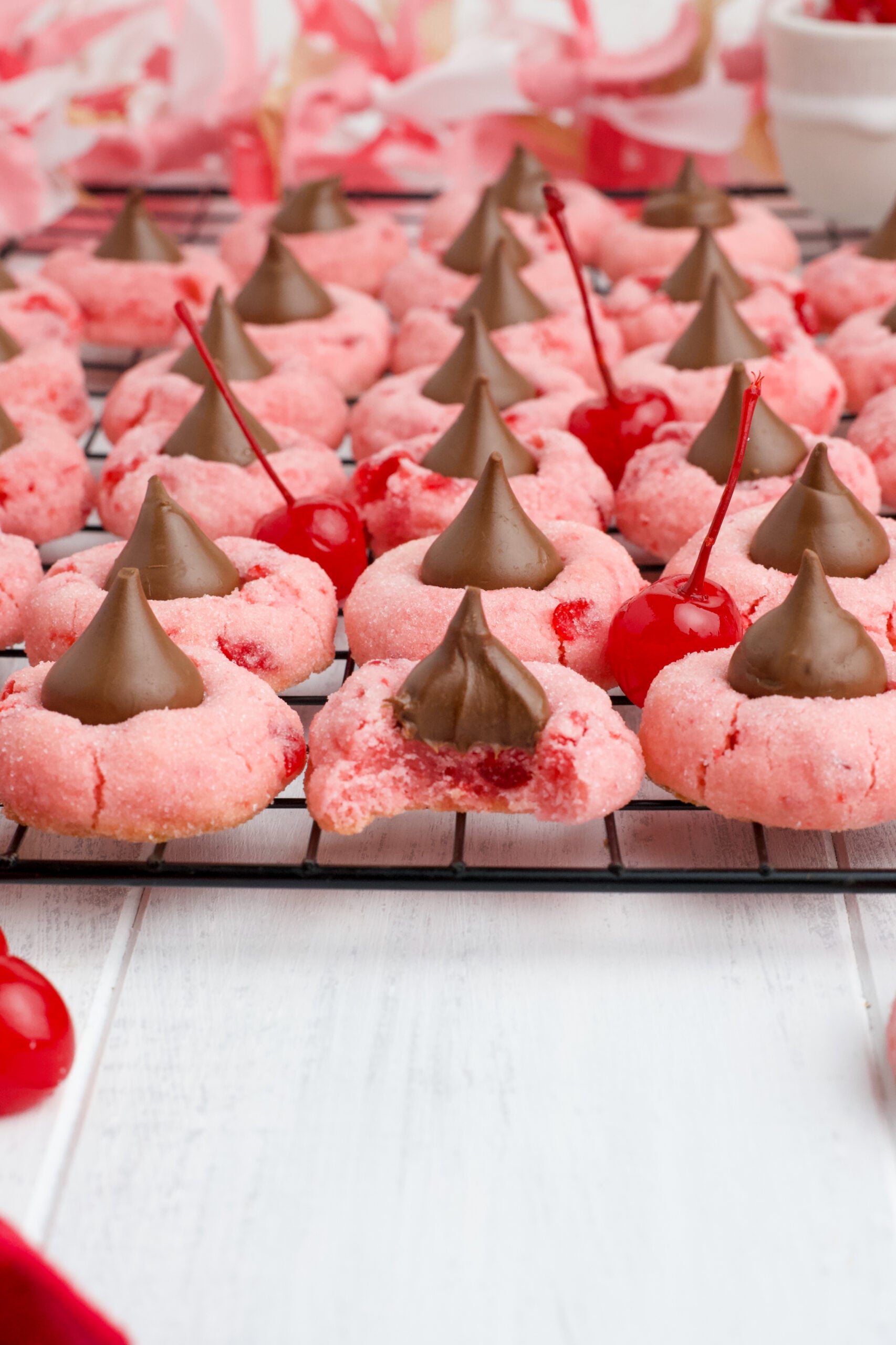Front view of Cherry Blossom Cookies on a black wire rack with a bite removed from the front cookie.