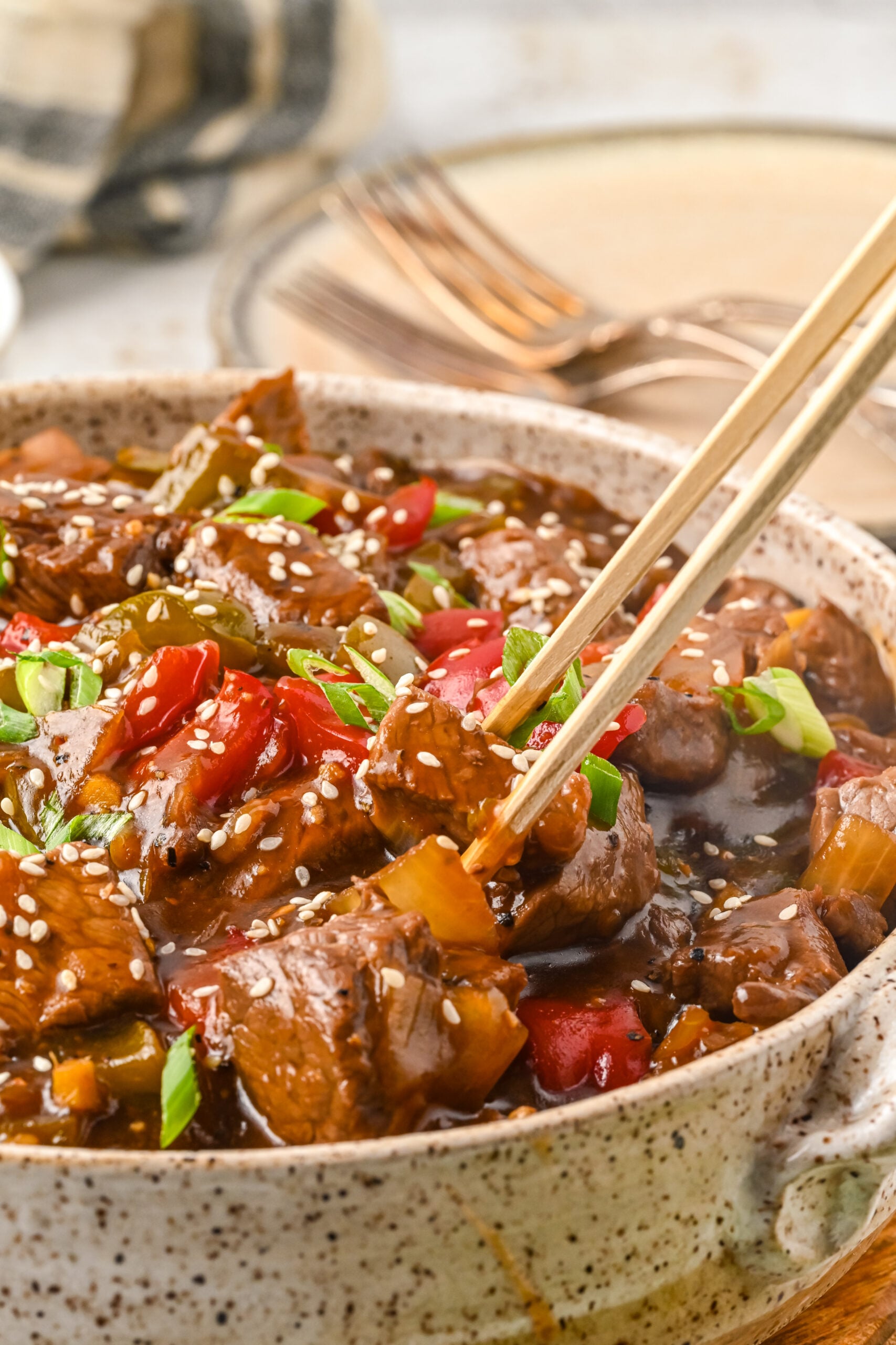 Close up view of chopsticks holding a piece of Chinese Pepper Steak.