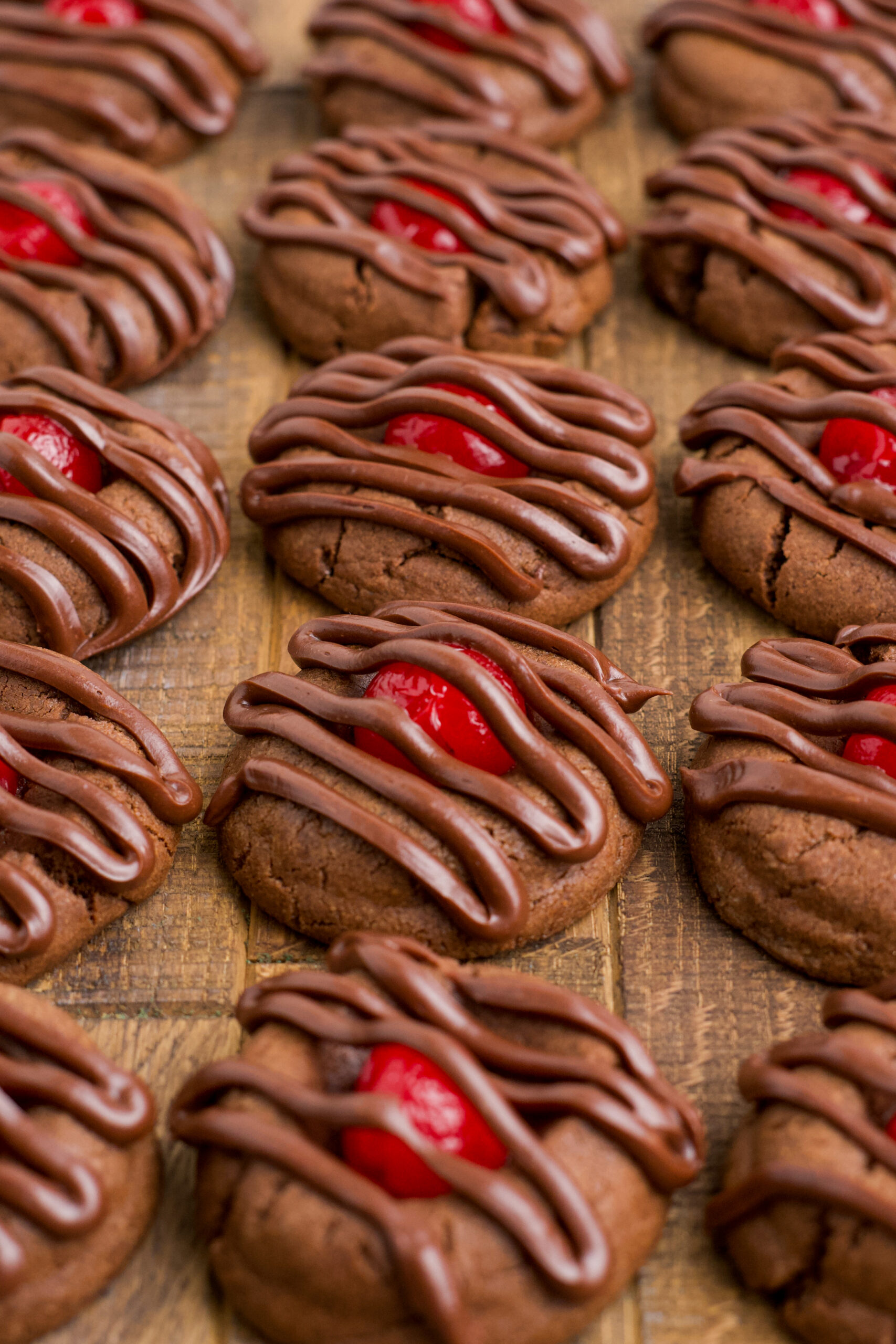 Chocolate Cherry Cookies lined up on a dark wood background. 