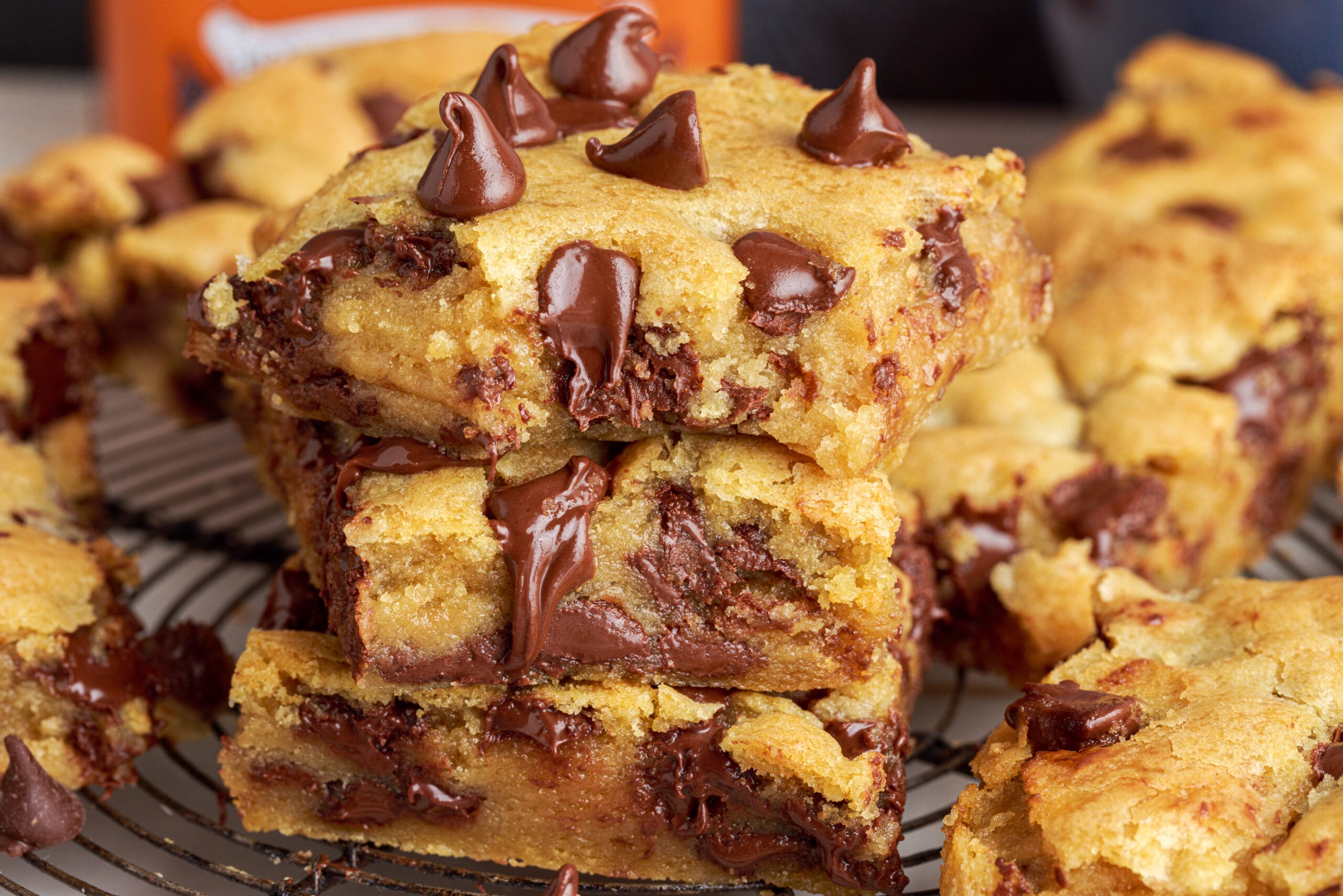Side view of three stacked chocolate chip cookie bars with a bite taken out of the top bar.