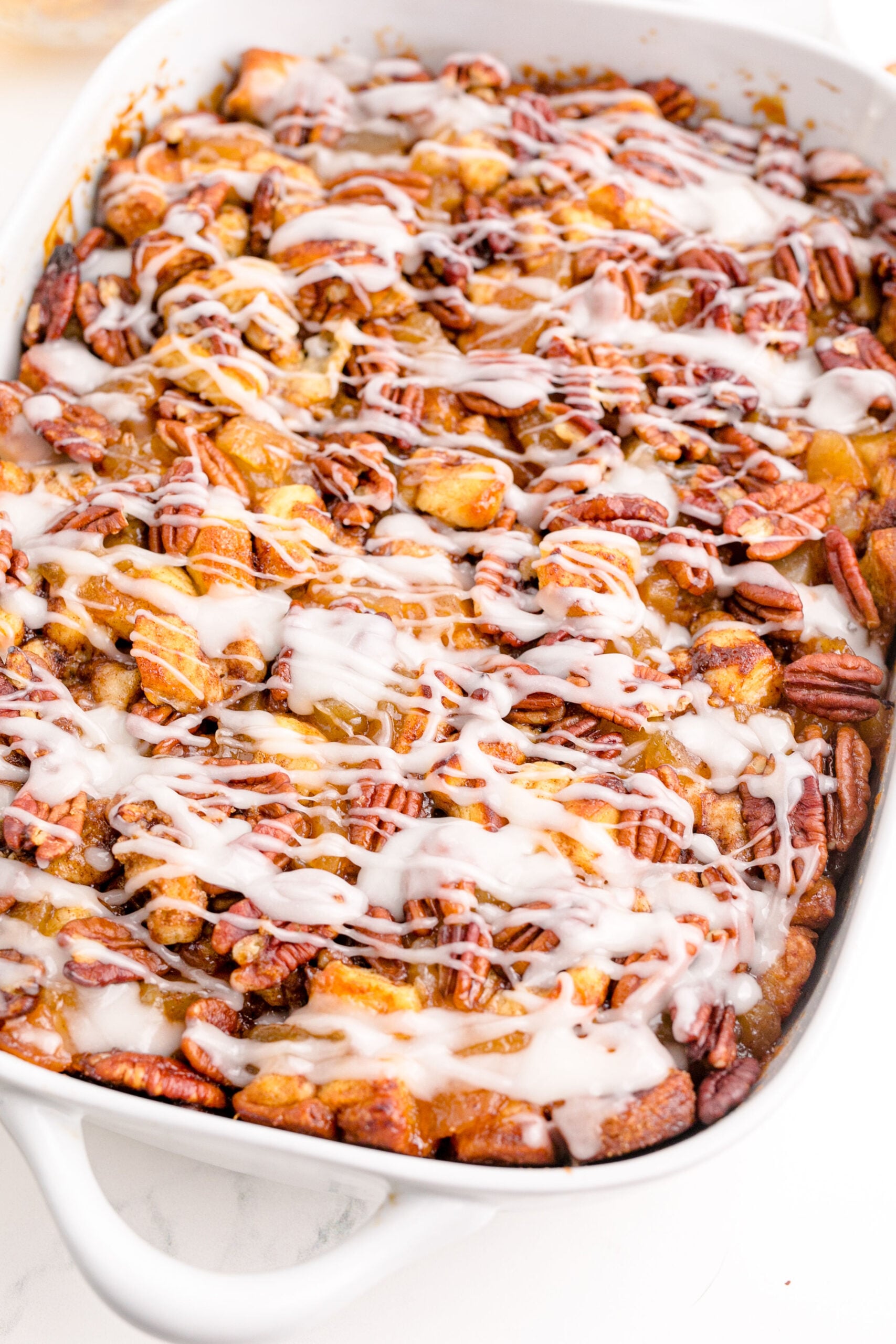 Cinnamon Roll Casserole in a white baking dish topped with icing.