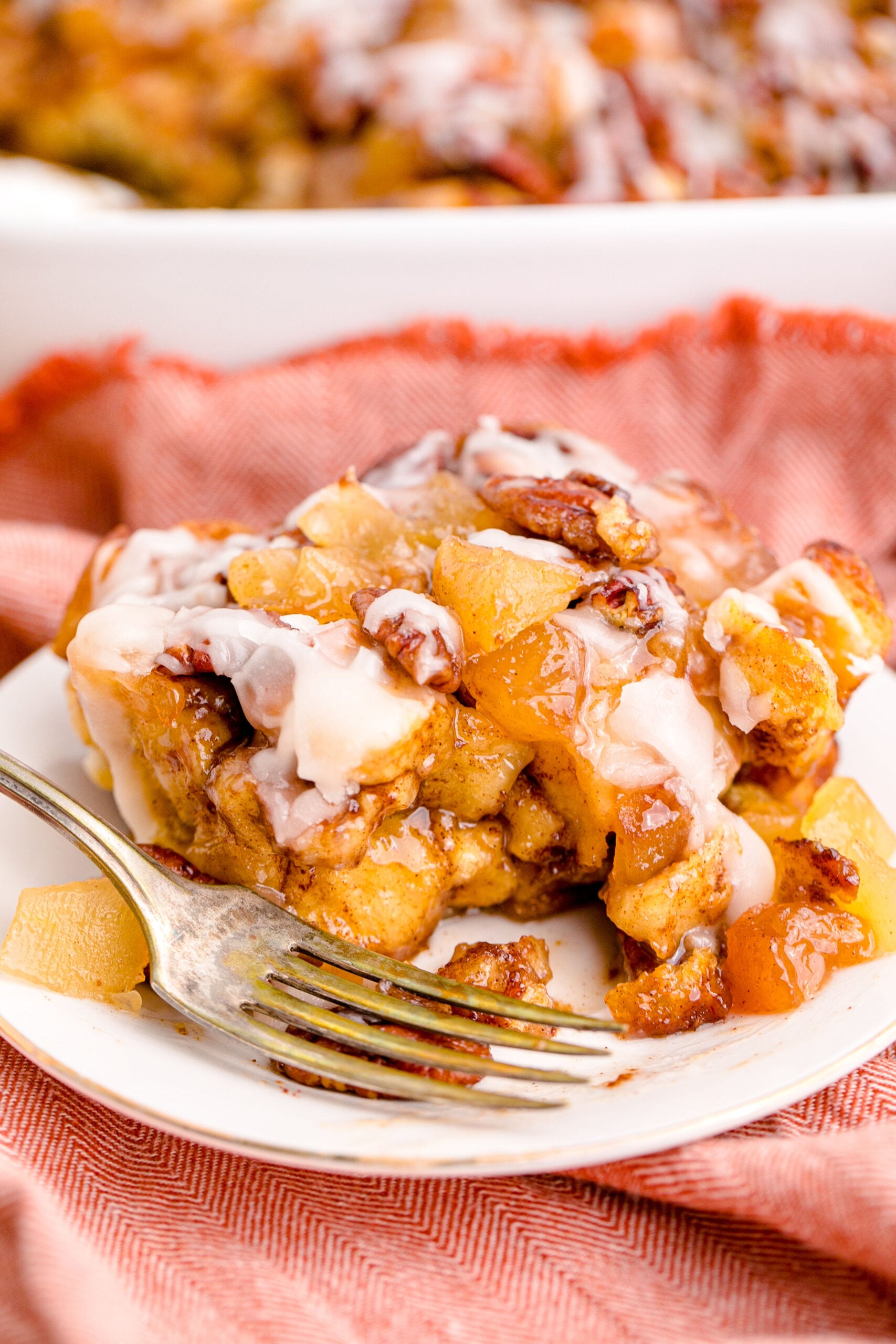 Cinnamon Roll Casserole on a white plate with a gold fork removing a bite.