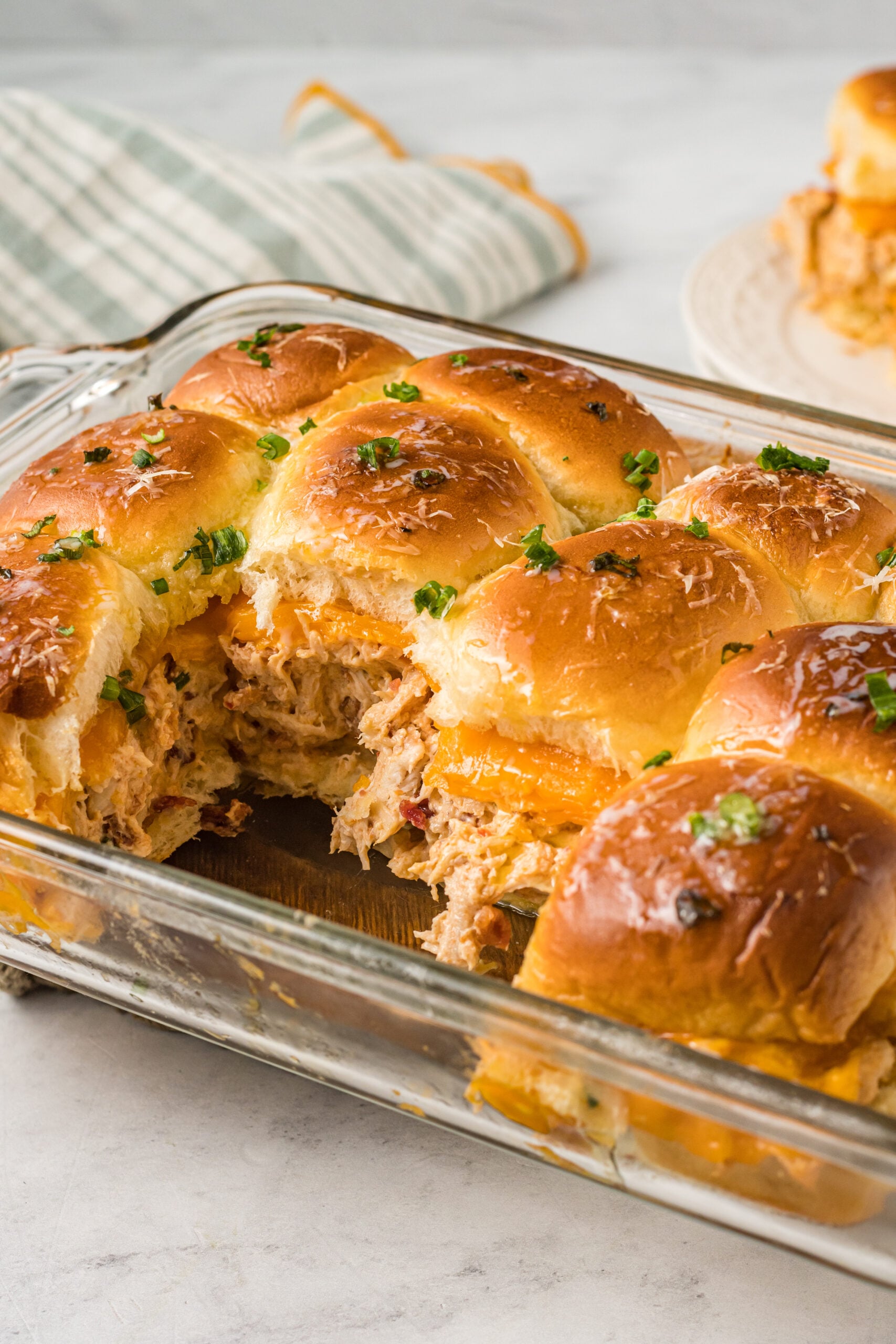 Side view of Crack Chicken Sliders in a clear baking dish.
