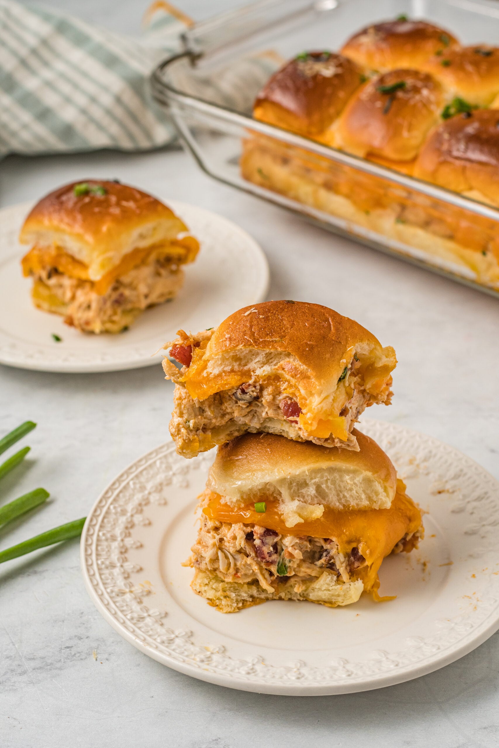 Front view of two Crack Chicken Sliders
stacked on a white plate with a bite removed from the top slider.