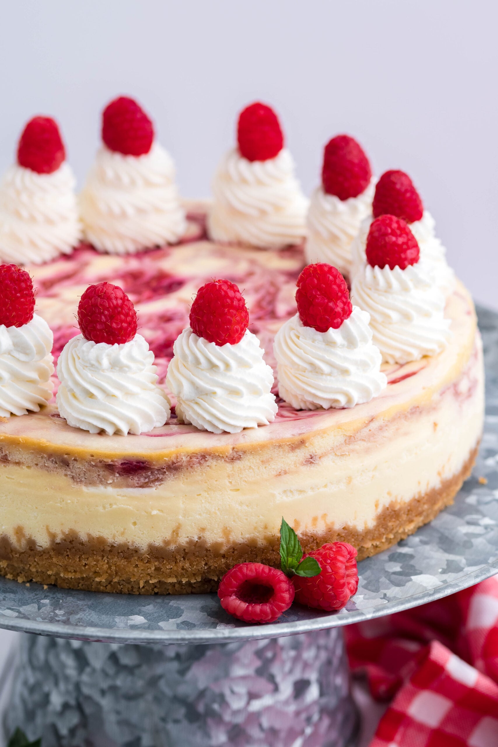 Close up side view of Raspberry Swirl Cheesecake on a galvanized cake stand.