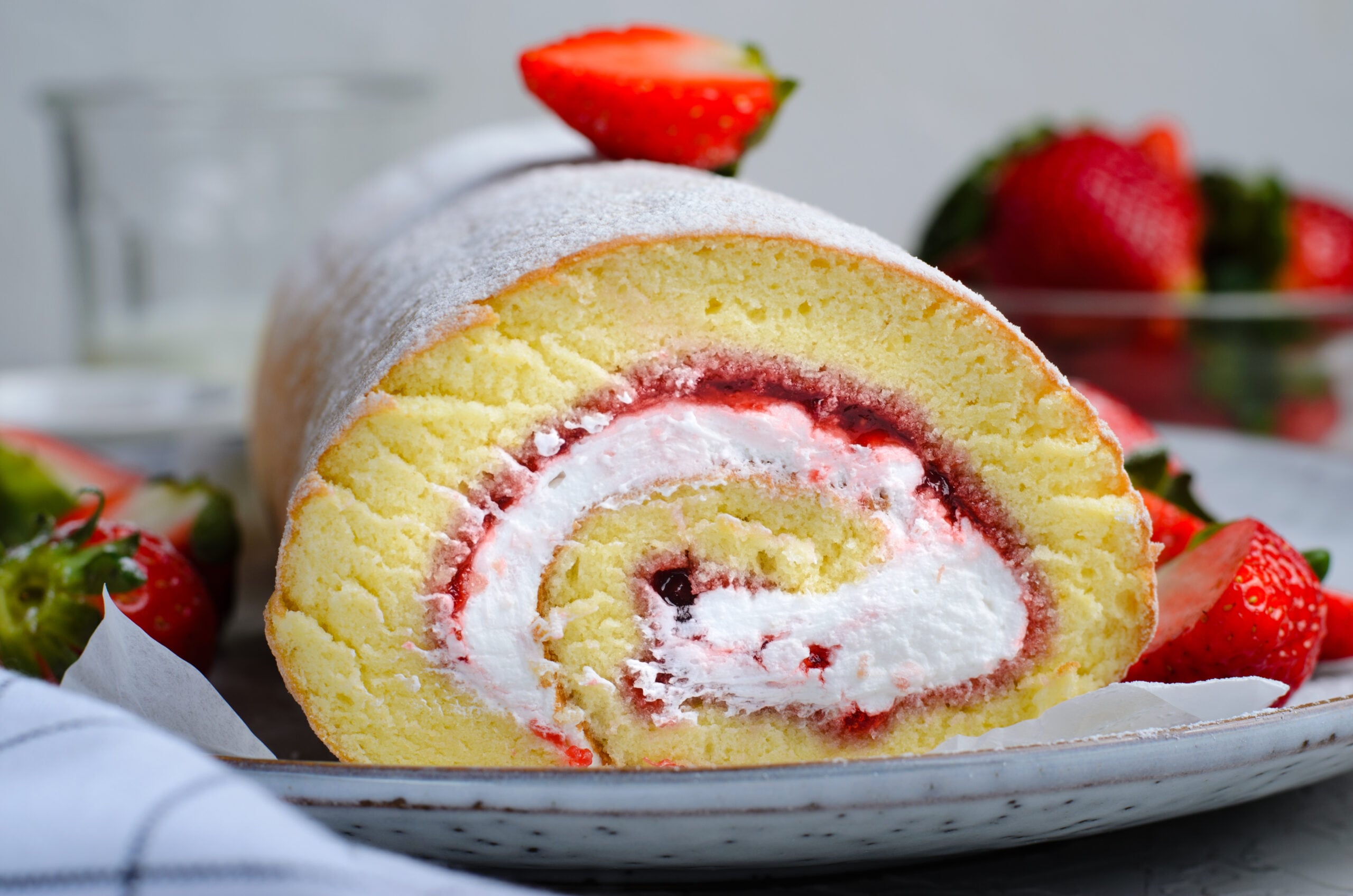 Front view of Strawberries & Cream Cake Roll on a white serving dish.