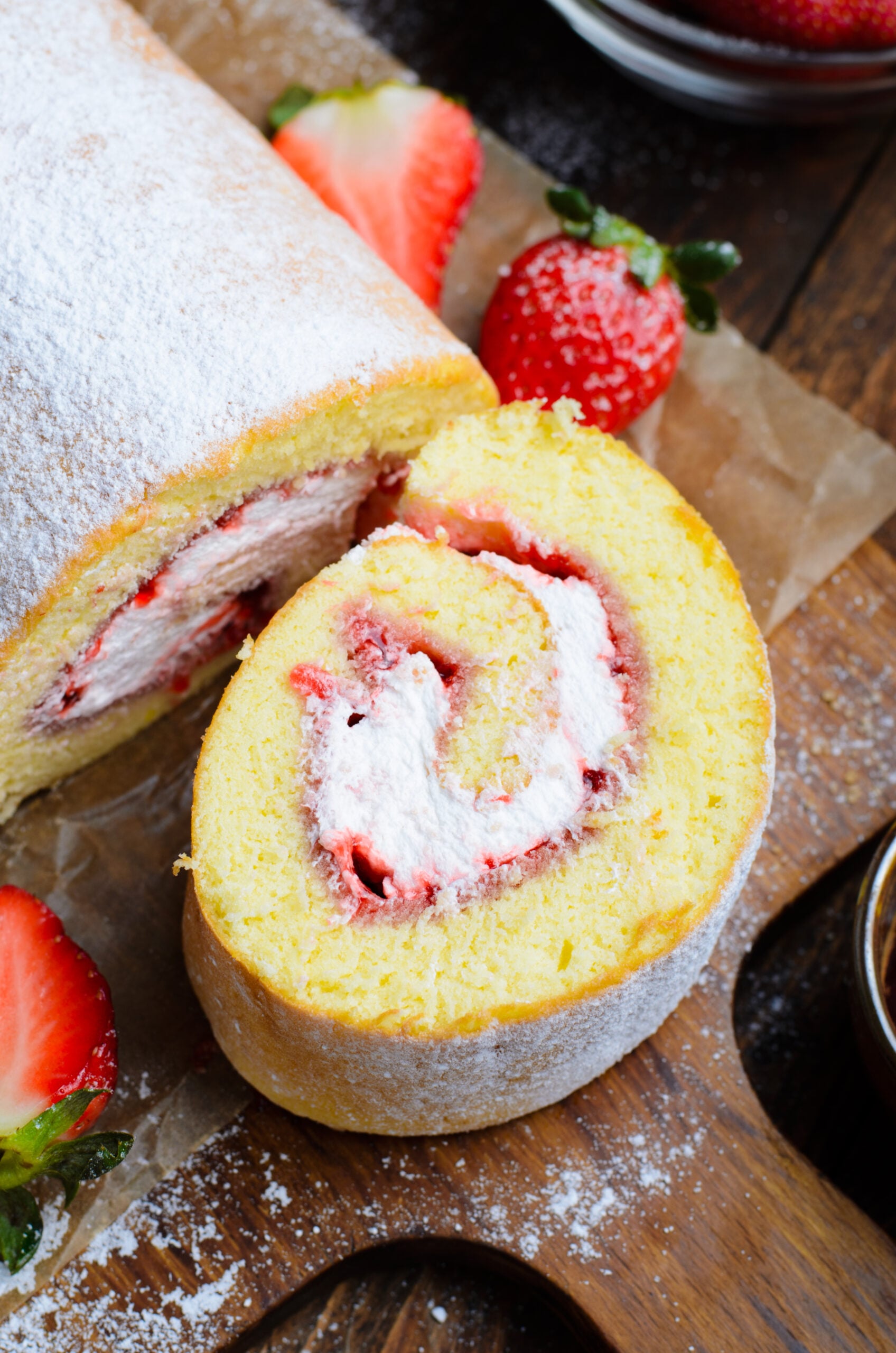 Overhead view of a slice of Strawberries & Cream Cake Roll on a piece of parchment paper.