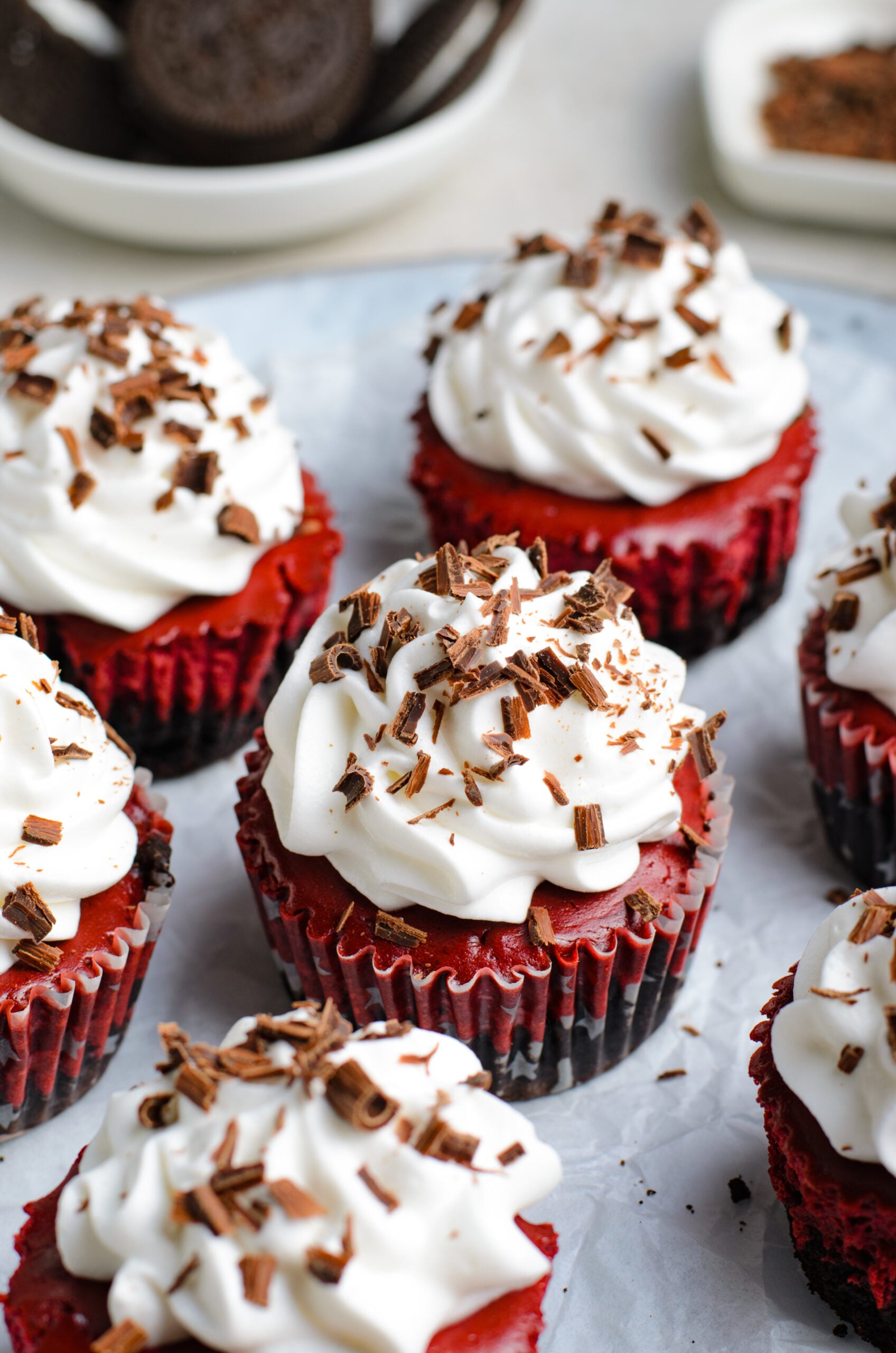 Close up view of Mini Red Velvet Oreo Cheesecakes on a piece of parchment paper.