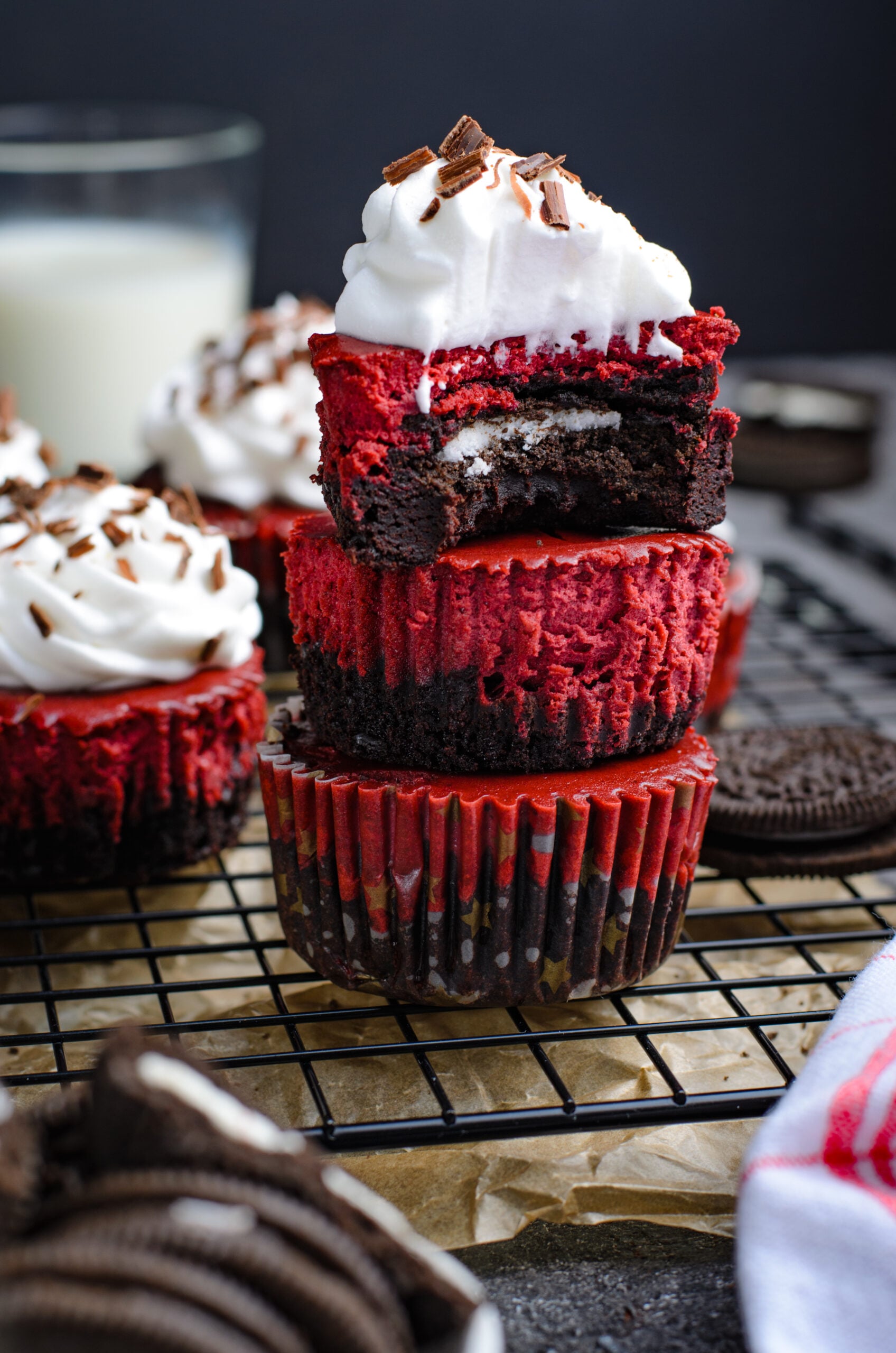 Front view of three Mini Red Velvet Oreo Cheesecakes stacked with a bite removed from the top cheesecake.