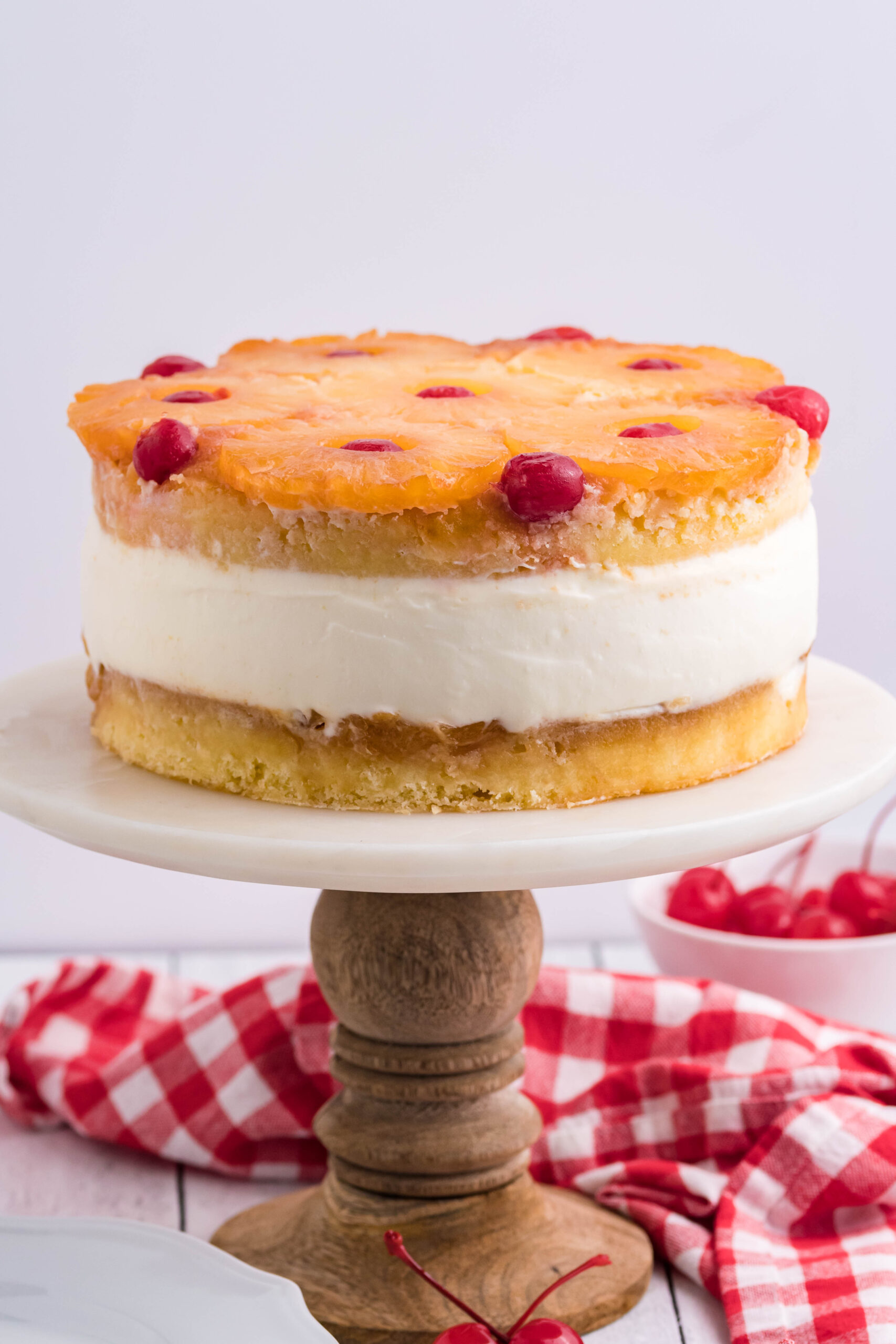 Front view of Pineapple Upside Down Cheesecake Cake on a white and wooden cake stand.