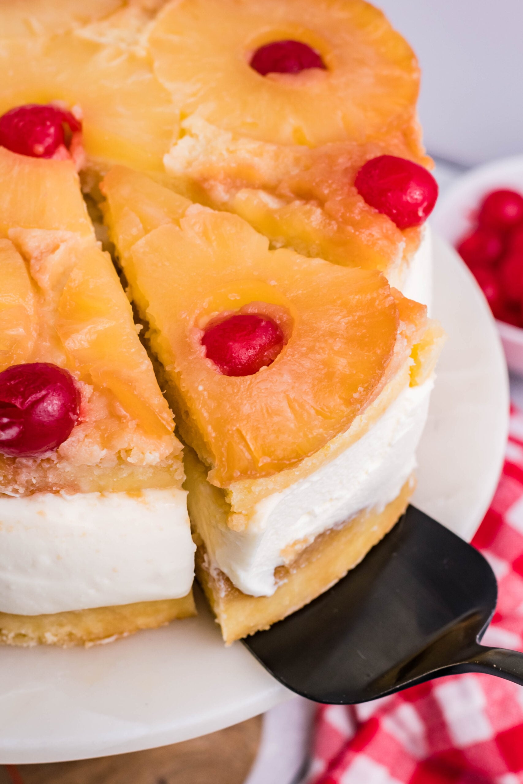 Up close view of a slice of Pineapple Upside Down Cheesecake Cake being removed with a black cake server.
