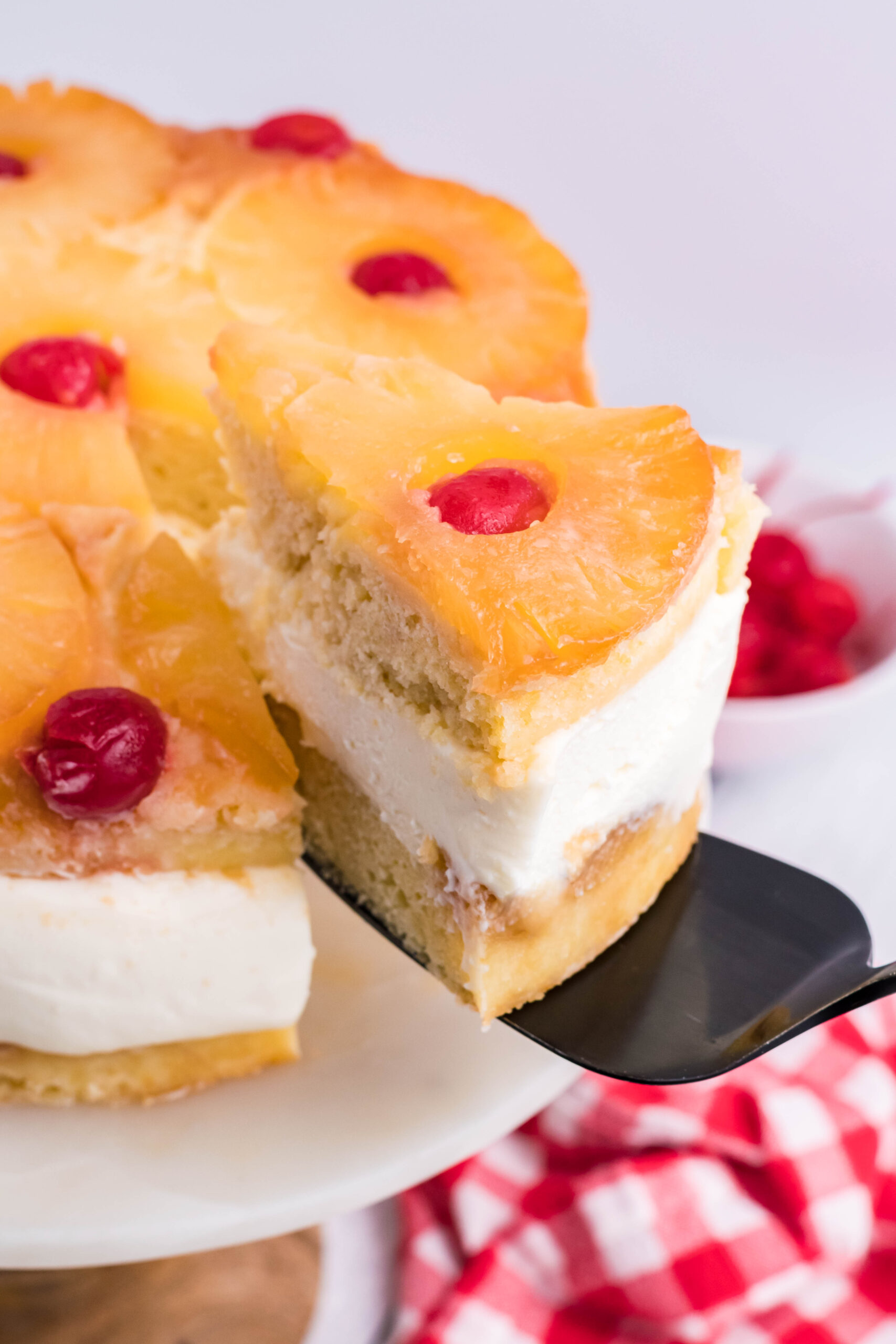 Up close view of a slice of Pineapple Upside Down Cheesecake Cake being removed with a black cake server.