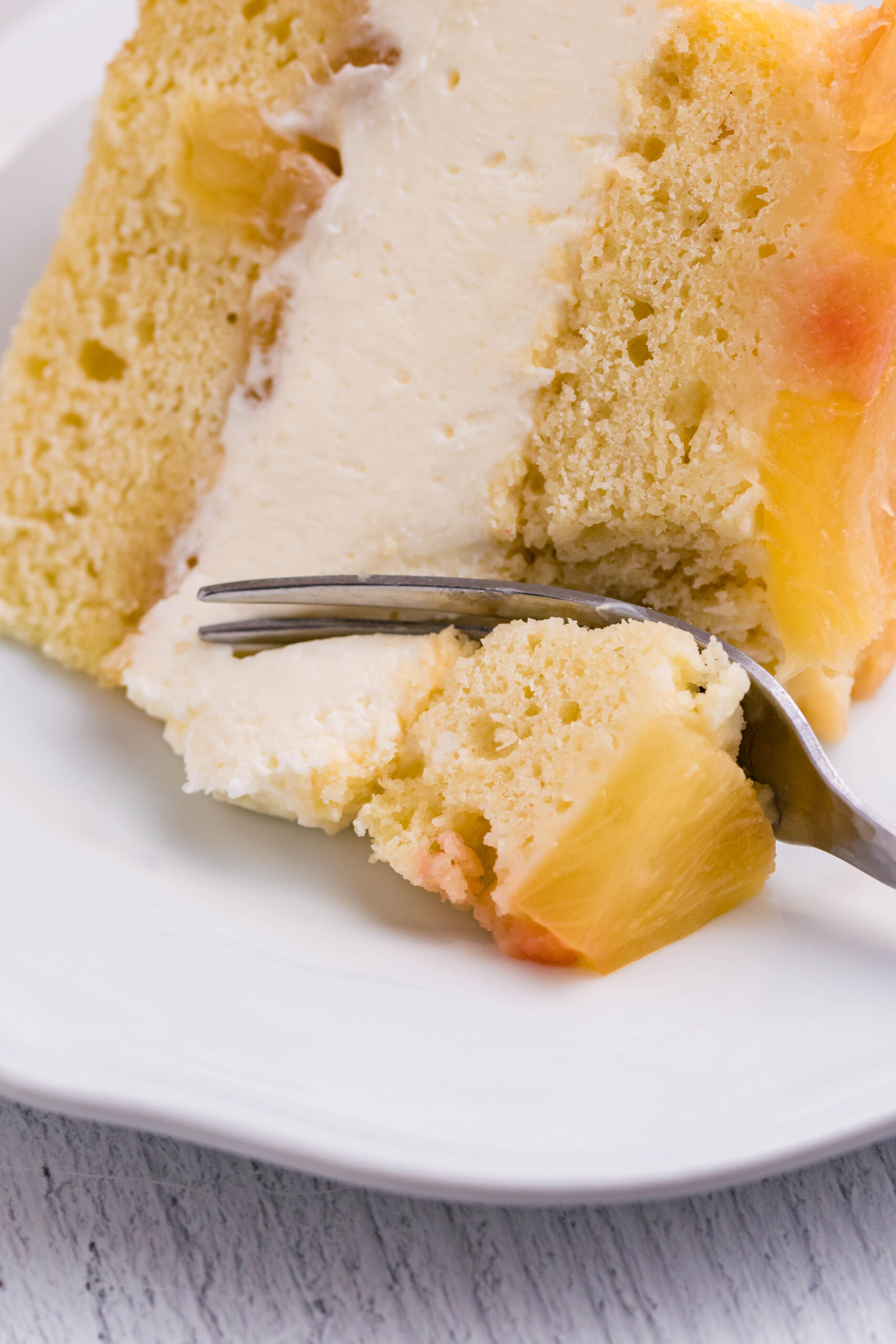 Up close view of a silver fork removing a bite from a slice of Pineapple Upside Down Cheesecake Cake.