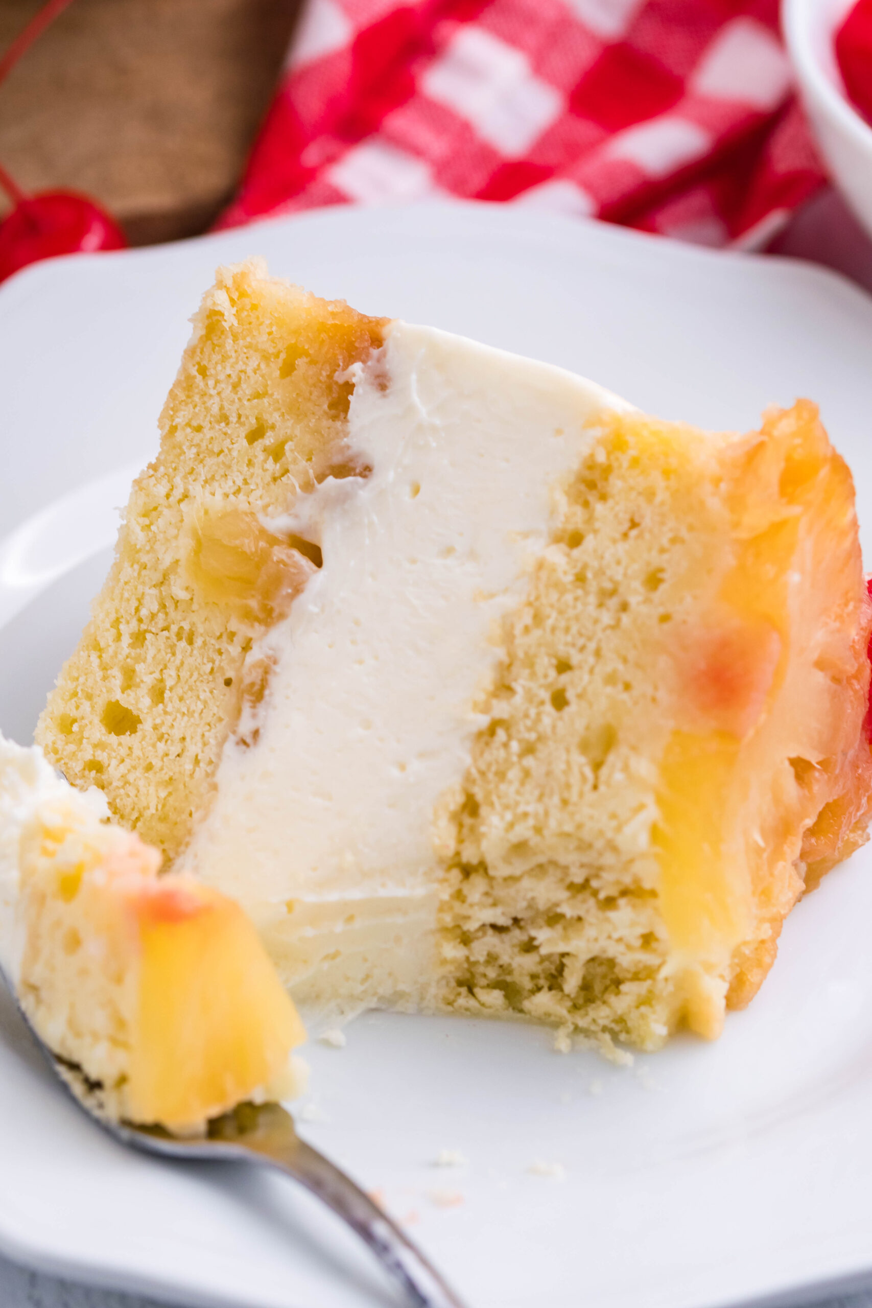 Up close view of a slice of Pineapple Upside Down Cheesecake Cake with a bite removed by a silver fork.