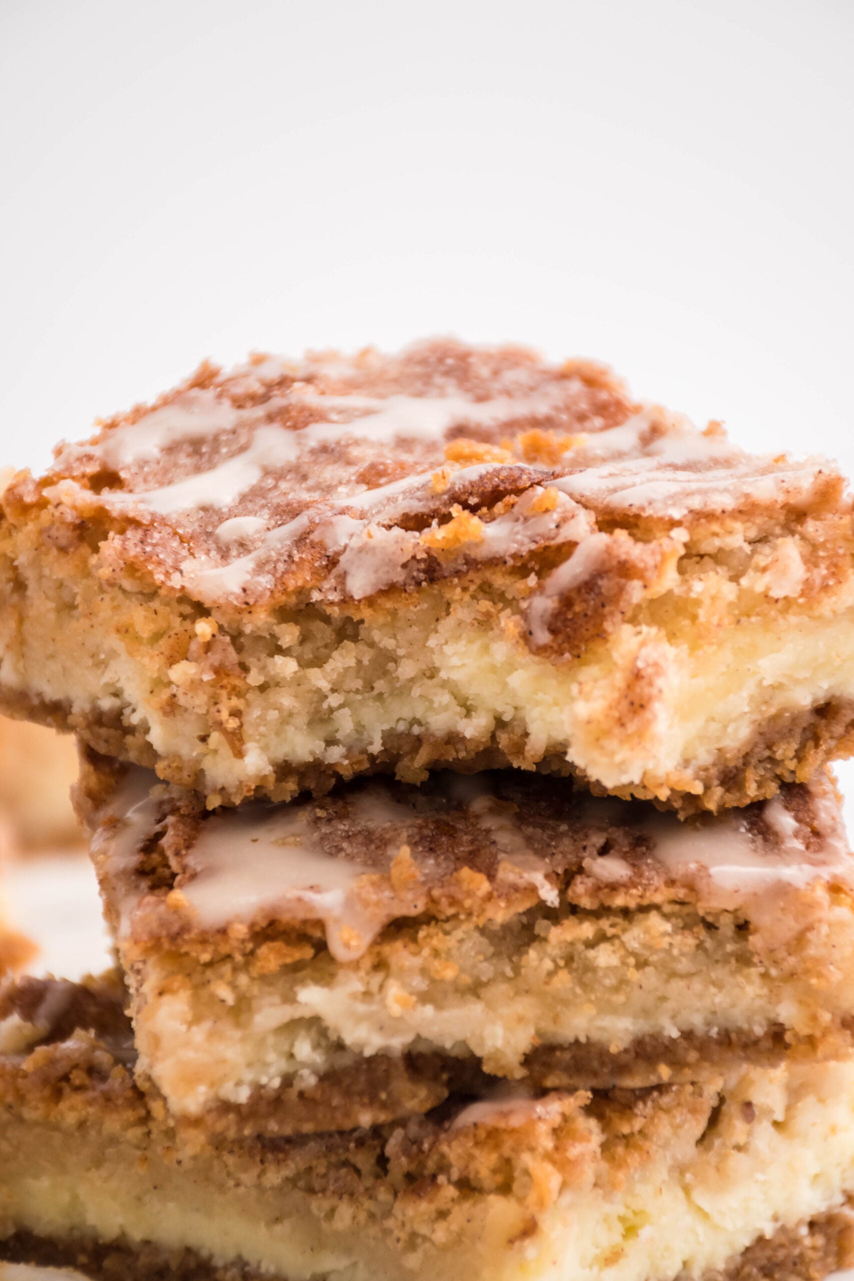 Front view of three Snickerdoodle Cheesecake Bars stacked with a bite removed from the top bar.