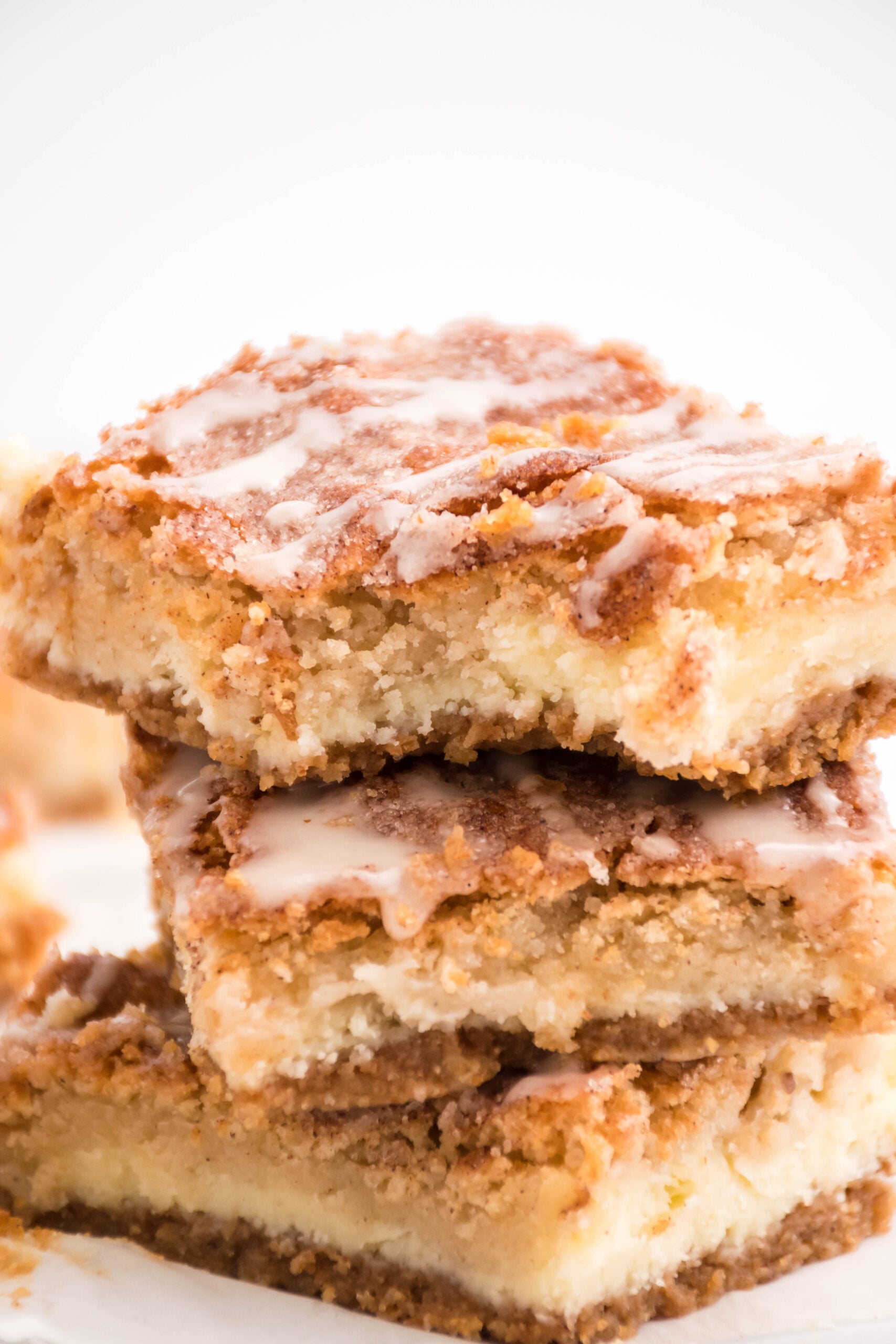 Front view of three Snickerdoodle Cheesecake Bars stacked with a bite removed from the top bar.
