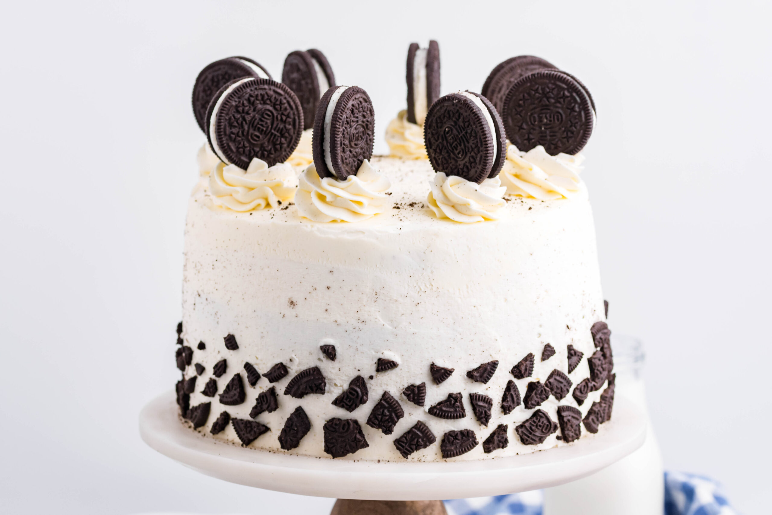 Front view of Double Stuffed Oreo Cake on a white and wood cake stand.