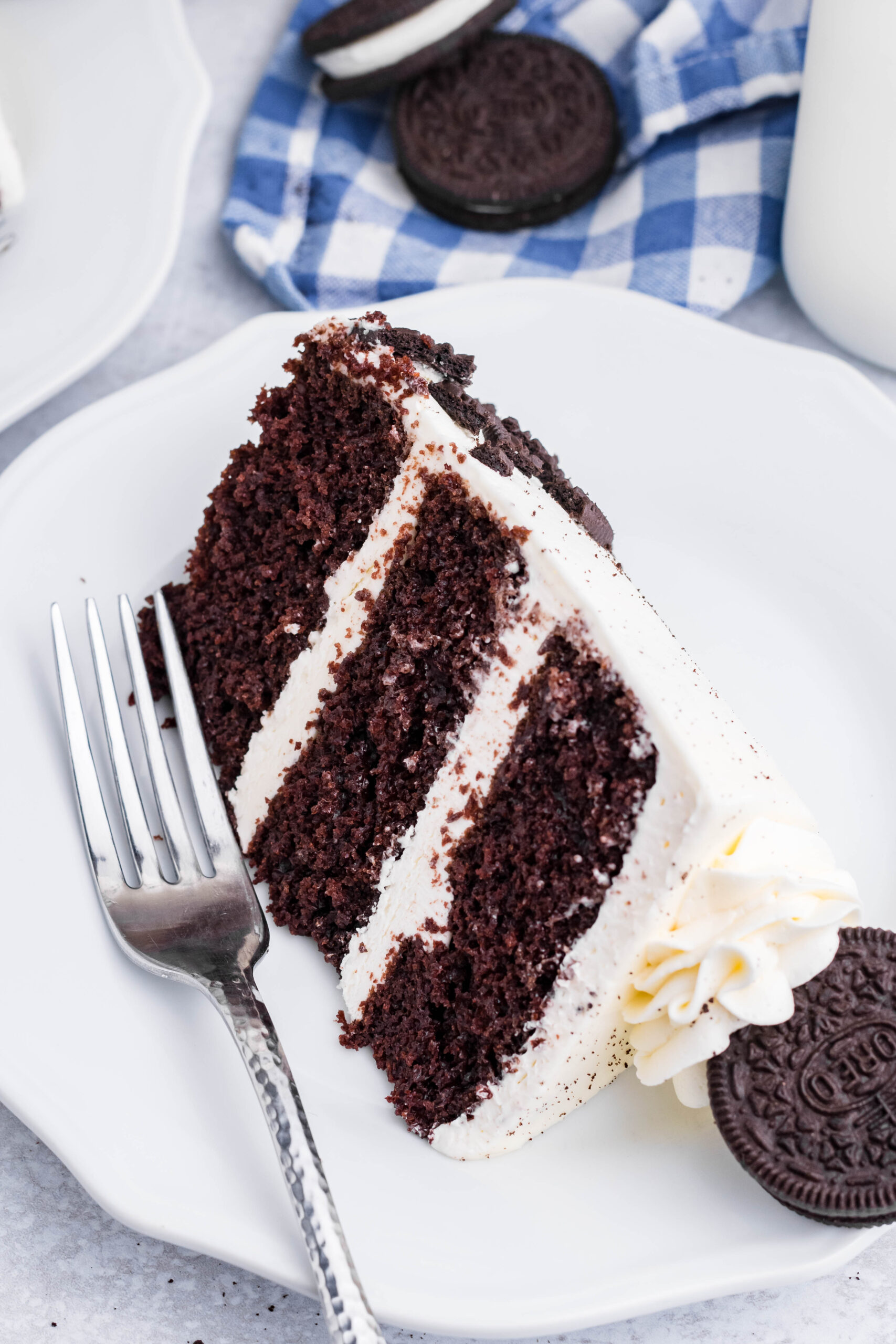 Overhead view of a slice of Double Stuffed Oreo Cake served on a white plate with a silver fork.